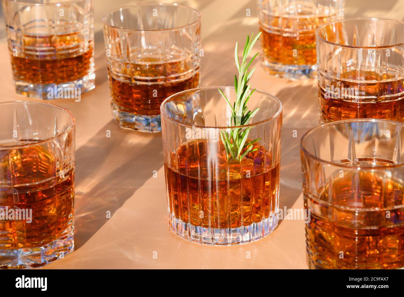 Molti bicchieri di whisky con rosmarino su beige. Foto Stock