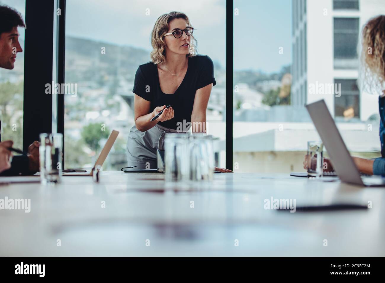 Imprenditrice donna che spiega le sue strategie ai colleghi della sala conferenze. donna d'affari che parla di lavoro con colleghi nella sala riunioni dell'ufficio. Foto Stock