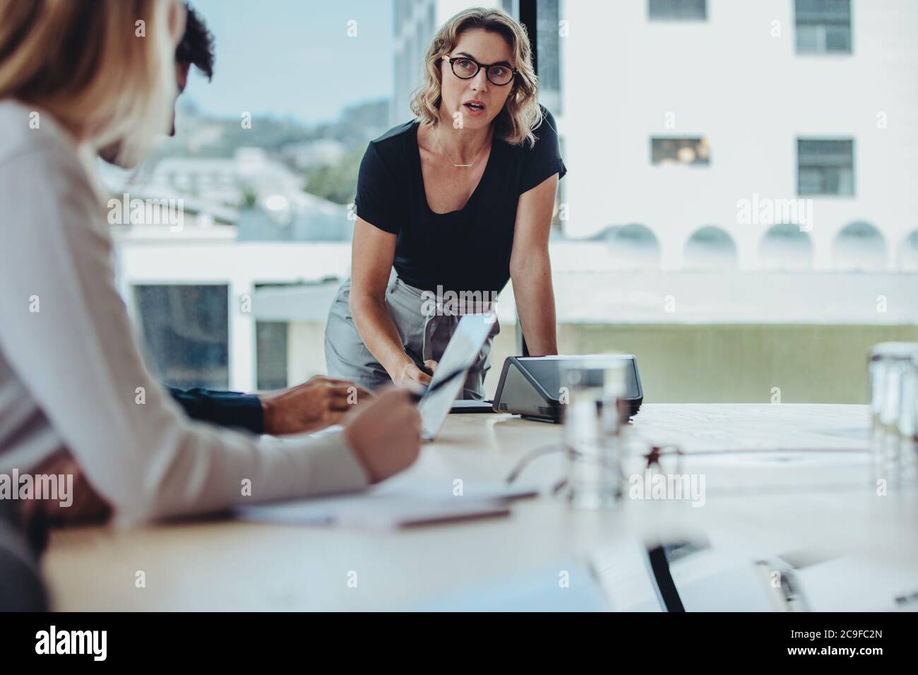 Donna che spiega nuove strategie ai colleghi durante la riunione. Uomini d'affari che si riunano nella sala del consiglio d'amministrazione per la discussione di nuovi progetti. Foto Stock