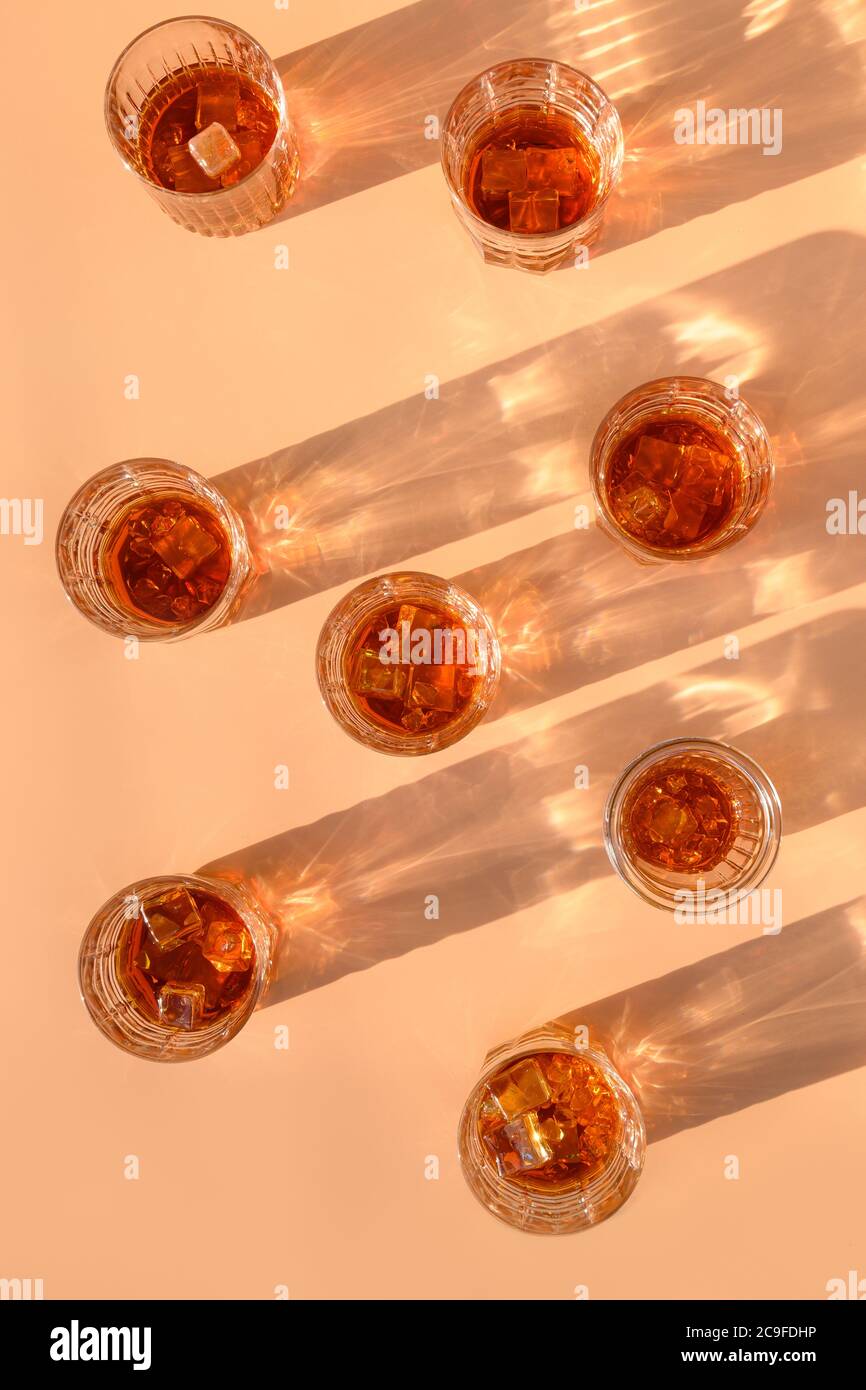 Molti bicchieri di whisky freddo serviti in rocce con rosmarino su sfondo beige trendy. Formato verticale. Foto Stock