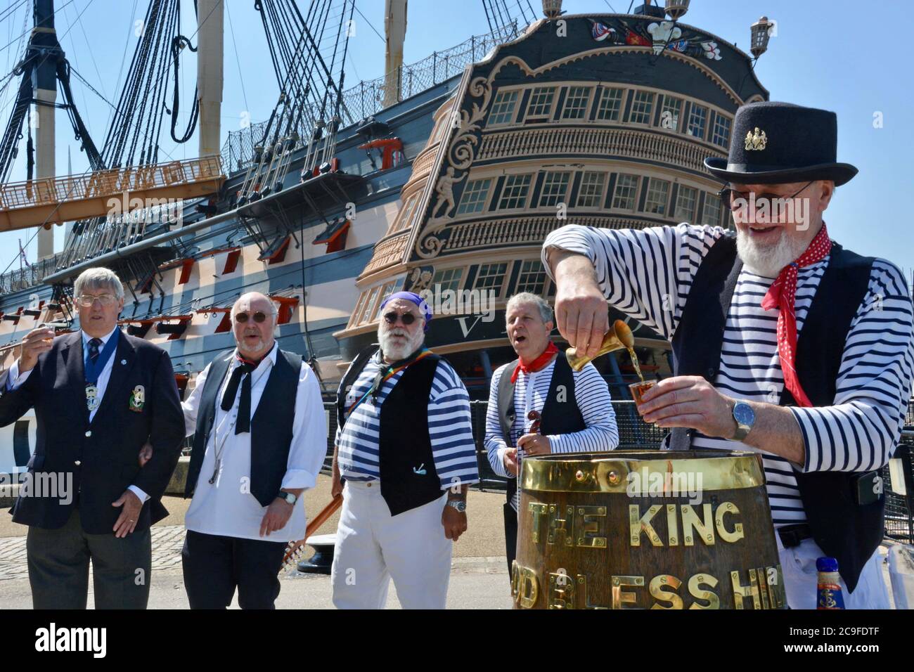 Keith Ridley, presidente nazionale della Royal Naval Association (a sinistra) lancia un tot di rum con la ÔAndsome Cabin Boys Sea Shanty band a Portsmouth Historic Dockyard per celebrare il 50 ° anniversario del Black Tot Day Ð il giorno in cui la Royal Navy ha smesso di emettere marinai la loro razione quotidiana al rum . Foto Stock