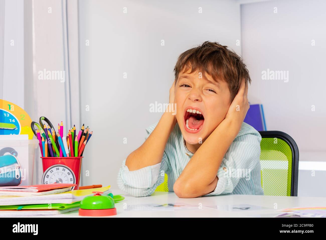 Urlando ragazzo triste con disturbo autistico coprire le orecchie e gridare durante la lezione di terapia di sviluppo Foto Stock