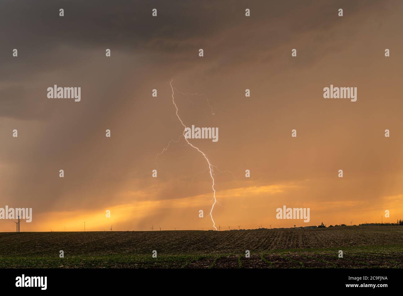 Una tempesta al tramonto passa sopra le grandi pianure mentre la pioggia e il fulmine scoppiato mettono in risalto l'orizzonte. Foto Stock