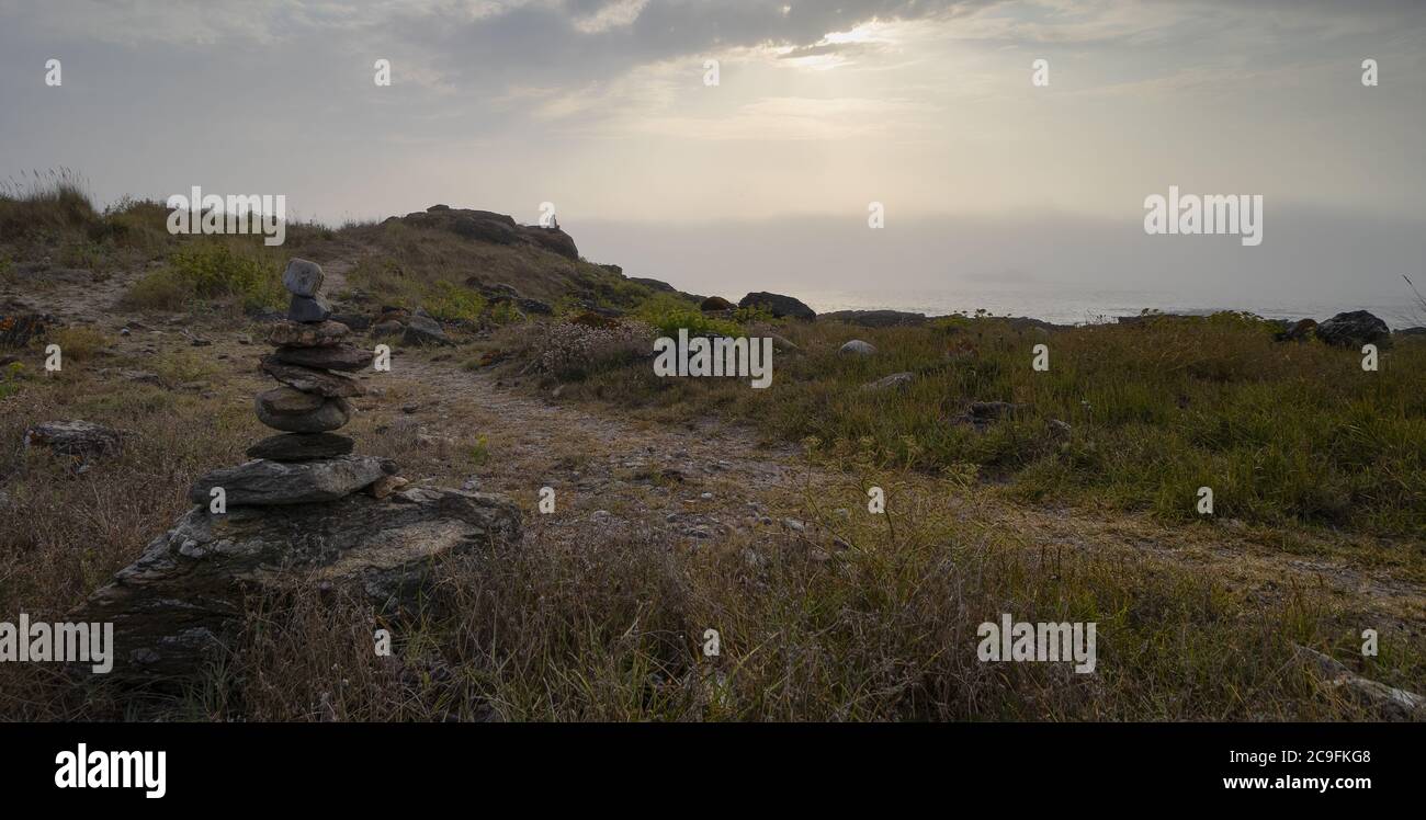 Foto a basso angolo di pietre accuratamente impilate in prateria nella costa della Galizia, Spagna Foto Stock