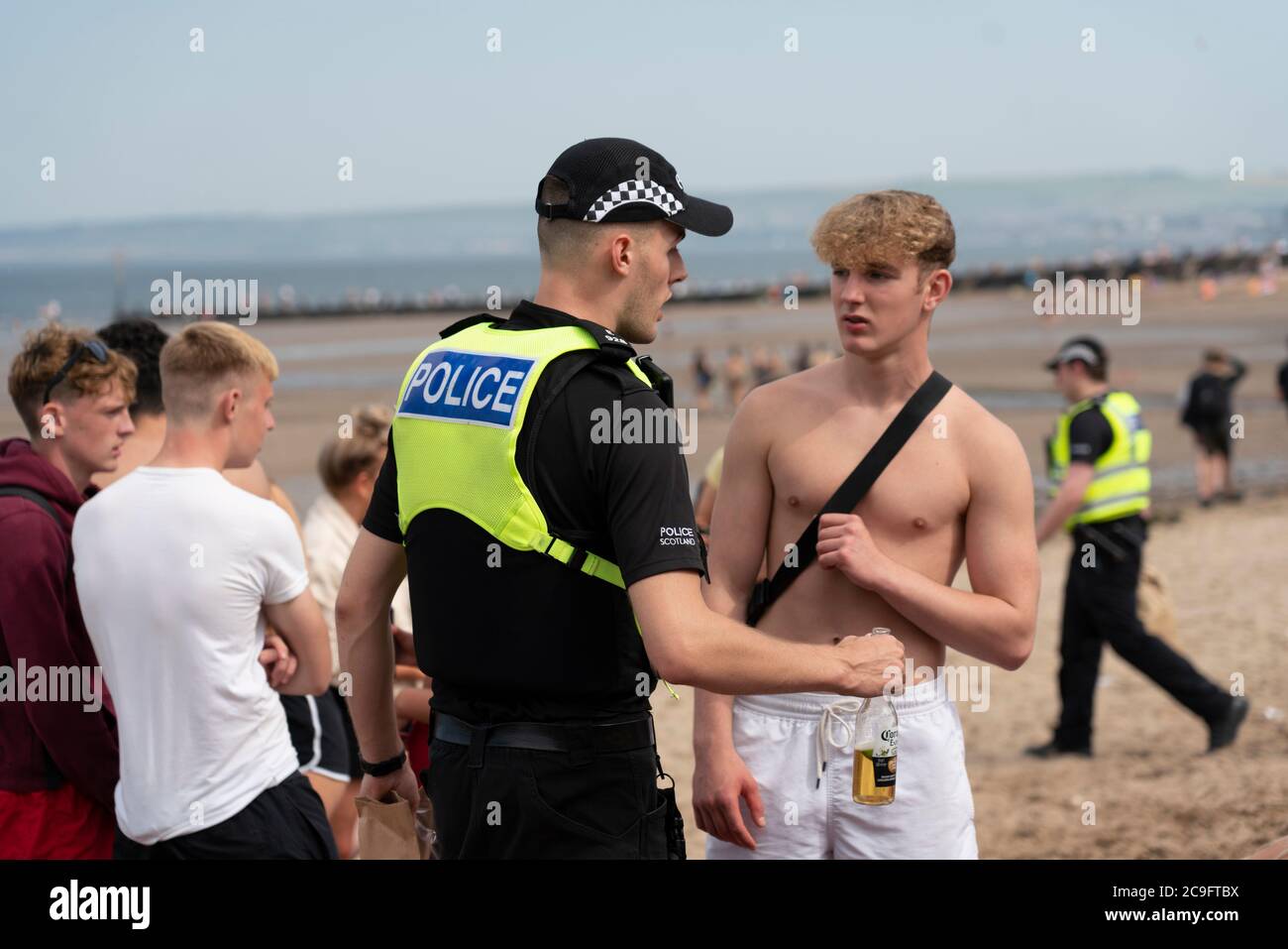 Edimburgo, Scozia, Regno Unito. 31 luglio 2020. La temperatura di 25°C e il sole hanno portato enormi folle a Portobello Beach fuori Edimburgo. Molti grandi gruppi di adolescenti stavano godendo la spiaggia e le bevande alcoliche erano molto popolari. Nella foto, intorno alle 15:00 si sono verificati problemi tra i giovani sulla spiaggia e i rinforzi della polizia sono stati rapidamente in scena e molte persone sono state rapite. Westbank Street è stata chiusa al traffico e circa 30 poliziotti stanno pattugliando la passeggiata. La polizia confisca l'alcool degli adolescenti che rimangono sulla spiaggia. Iain Masterton/Alamy Live News Foto Stock