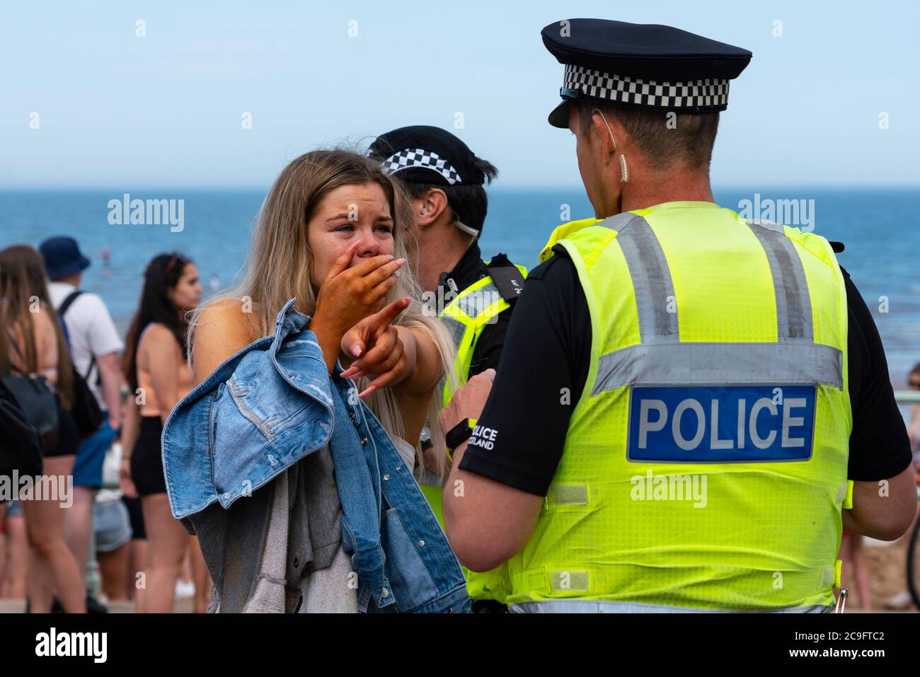 Edimburgo, Scozia, Regno Unito. 31 luglio 2020. La temperatura di 25°C e il sole hanno portato enormi folle a Portobello Beach fuori Edimburgo. Molti grandi gruppi di adolescenti stavano godendo la spiaggia e le bevande alcoliche erano molto popolari. Nella foto, intorno alle 15:00 si sono verificati problemi tra i giovani sulla spiaggia e i rinforzi della polizia sono stati rapidamente in scena e molte persone sono state rapite. Westbank Street è stata chiusa al traffico e circa 30 poliziotti stanno pattugliando la passeggiata. La polizia confisca l'alcool degli adolescenti che rimangono sulla spiaggia. Iain Masterton/Alamy Live News Foto Stock