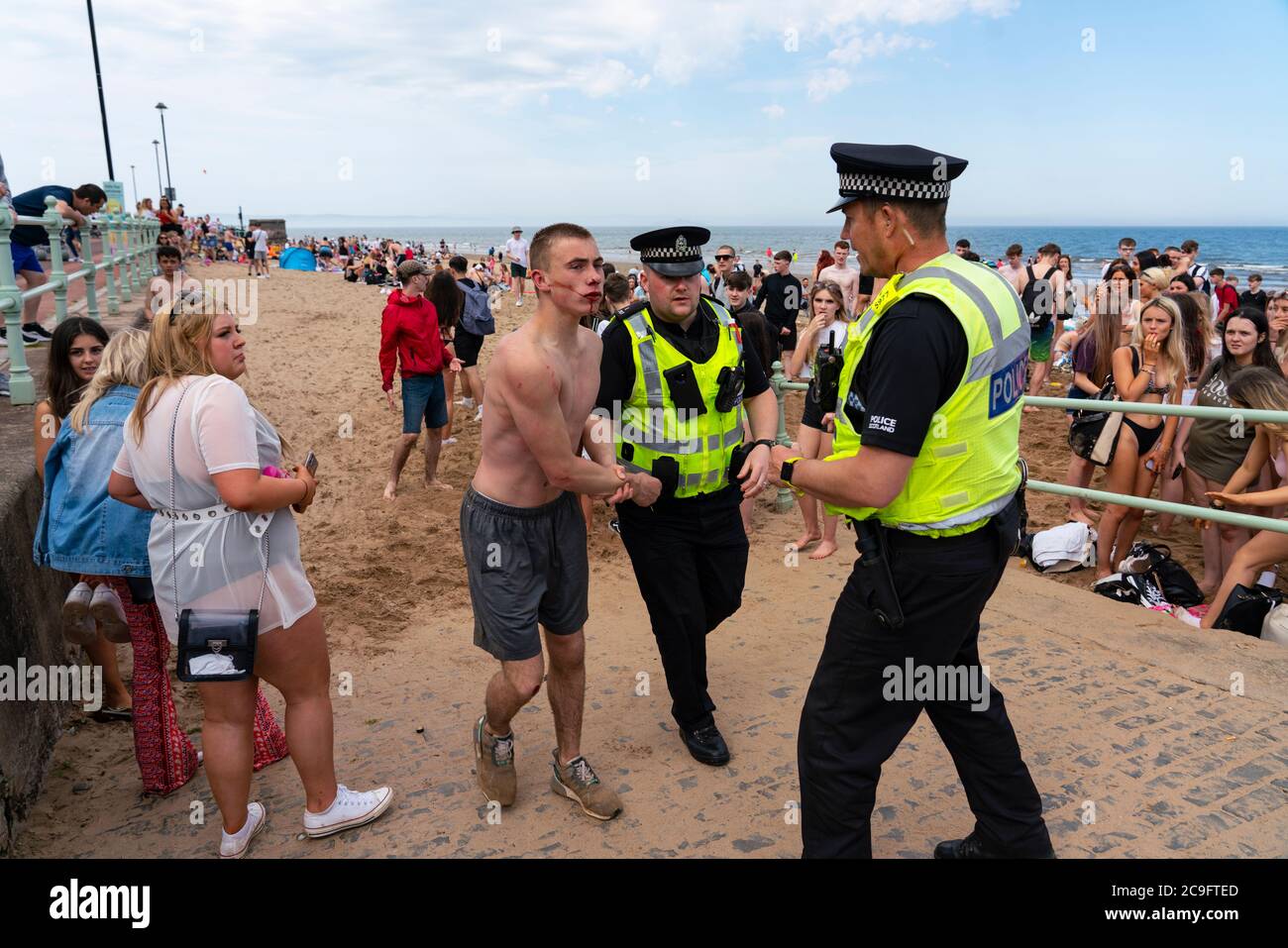 Edimburgo, Scozia, Regno Unito. 31 luglio 2020. La temperatura di 25°C e il sole hanno portato enormi folle a Portobello Beach fuori Edimburgo. Molti grandi gruppi di adolescenti stavano godendo la spiaggia e le bevande alcoliche erano molto popolari. Nella foto, intorno alle 15:00 si sono verificati problemi tra i giovani sulla spiaggia e i rinforzi della polizia sono stati rapidamente in scena e molte persone sono state rapite. Westbank Street è stata chiusa al traffico e circa 30 poliziotti stanno pattugliando la passeggiata. La polizia confisca l'alcool degli adolescenti che rimangono sulla spiaggia. Iain Masterton/Alamy Live News Foto Stock