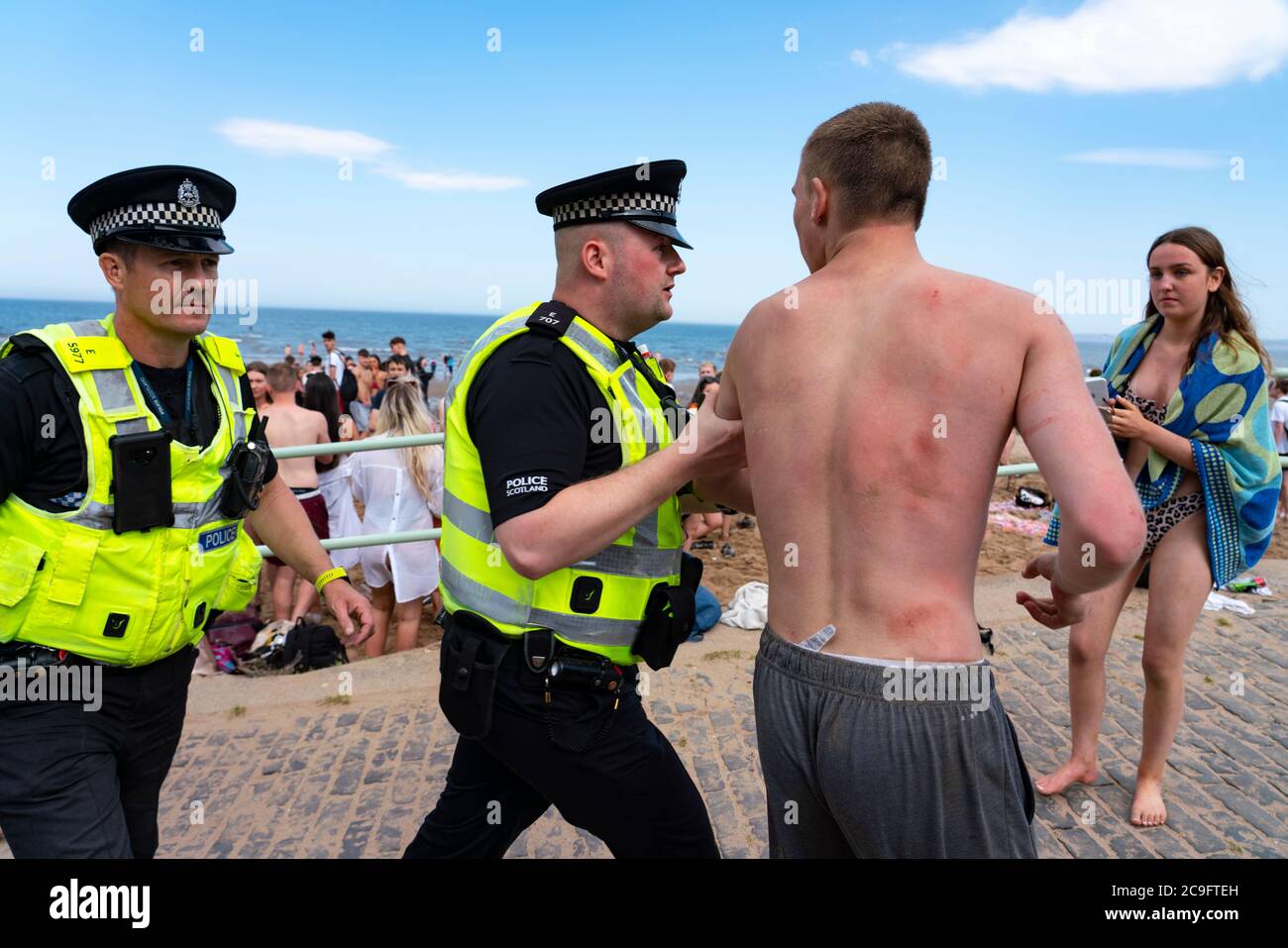 Edimburgo, Scozia, Regno Unito. 31 luglio 2020. La temperatura di 25°C e il sole hanno portato enormi folle a Portobello Beach fuori Edimburgo. Molti grandi gruppi di adolescenti stavano godendo la spiaggia e le bevande alcoliche erano molto popolari. Nella foto, intorno alle 15:00 si sono verificati problemi tra i giovani sulla spiaggia e i rinforzi della polizia sono stati rapidamente in scena e molte persone sono state rapite. Westbank Street è stata chiusa al traffico e circa 30 poliziotti stanno pattugliando la passeggiata. La polizia confisca l'alcool degli adolescenti che rimangono sulla spiaggia. Iain Masterton/Alamy Live News Foto Stock