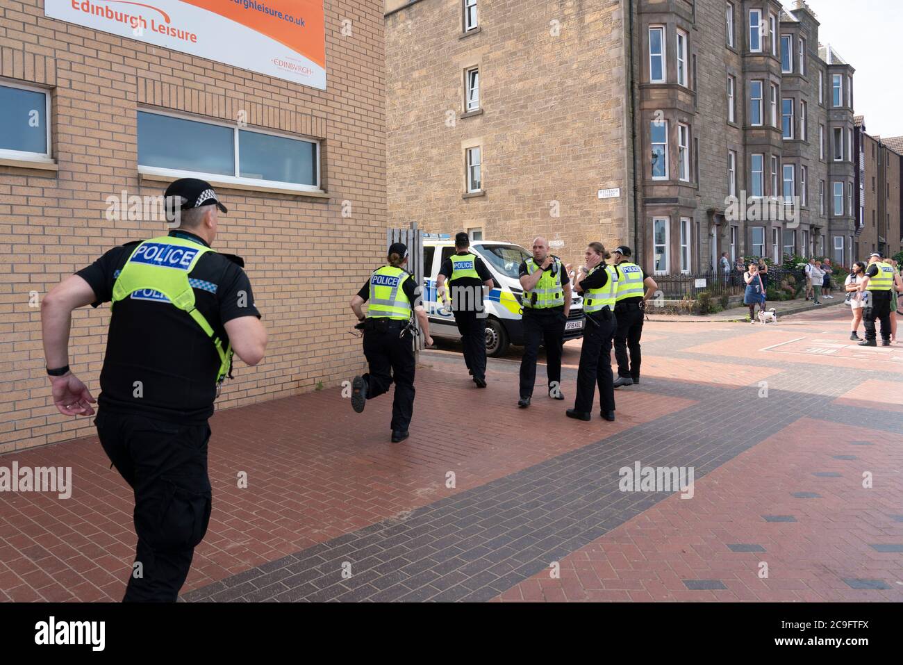 Edimburgo, Scozia, Regno Unito. 31 luglio 2020. La temperatura di 25°C e il sole hanno portato enormi folle a Portobello Beach fuori Edimburgo. Molti grandi gruppi di adolescenti stavano godendo la spiaggia e le bevande alcoliche erano molto popolari. Nella foto, intorno alle 15:00 si sono verificati problemi tra i giovani sulla spiaggia e i rinforzi della polizia sono stati rapidamente in scena e molte persone sono state rapite. Westbank Street è stata chiusa al traffico e circa 30 poliziotti stanno pattugliando la passeggiata. La polizia confisca l'alcool degli adolescenti che rimangono sulla spiaggia. Iain Masterton/Alamy Live News Foto Stock
