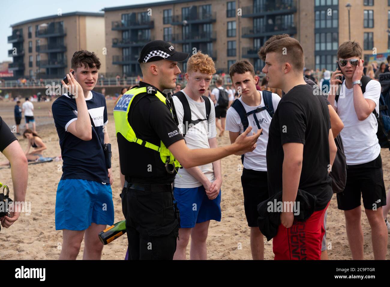 Edimburgo, Scozia, Regno Unito. 31 luglio 2020. La temperatura di 25°C e il sole hanno portato enormi folle a Portobello Beach fuori Edimburgo. Molti grandi gruppi di adolescenti stavano godendo la spiaggia e le bevande alcoliche erano molto popolari. Nella foto, intorno alle 15:00 si sono verificati problemi tra i giovani sulla spiaggia e i rinforzi della polizia sono stati rapidamente in scena e molte persone sono state rapite. Westbank Street è stata chiusa al traffico e circa 30 poliziotti stanno pattugliando la passeggiata. La polizia confisca l'alcool degli adolescenti che rimangono sulla spiaggia. Iain Masterton/Alamy Live News Foto Stock