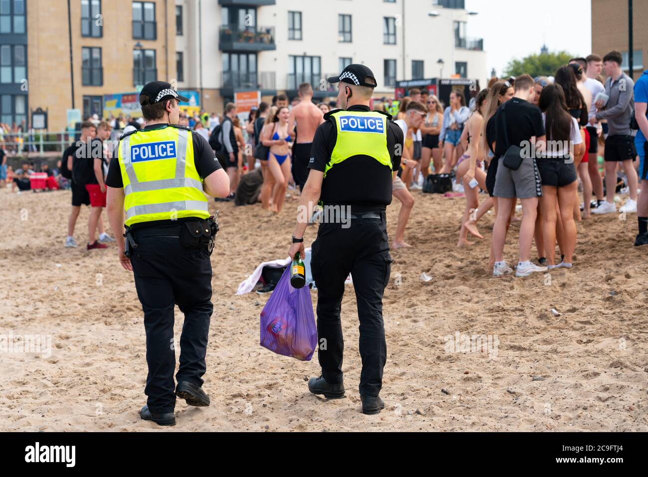 Edimburgo, Scozia, Regno Unito. 31 luglio 2020. La temperatura di 25°C e il sole hanno portato enormi folle a Portobello Beach fuori Edimburgo. Molti grandi gruppi di adolescenti stavano godendo la spiaggia e le bevande alcoliche erano molto popolari. Nella foto, intorno alle 15:00 si sono verificati problemi tra i giovani sulla spiaggia e i rinforzi della polizia sono stati rapidamente in scena e molte persone sono state rapite. Westbank Street è stata chiusa al traffico e circa 30 poliziotti stanno pattugliando la passeggiata. La polizia confisca l'alcool degli adolescenti che rimangono sulla spiaggia. Iain Masterton/Alamy Live News Foto Stock