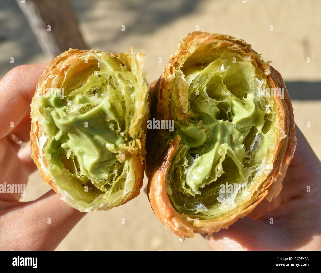Primo piano di due metà di un croissant con pistacchio ripieno di crema Foto Stock