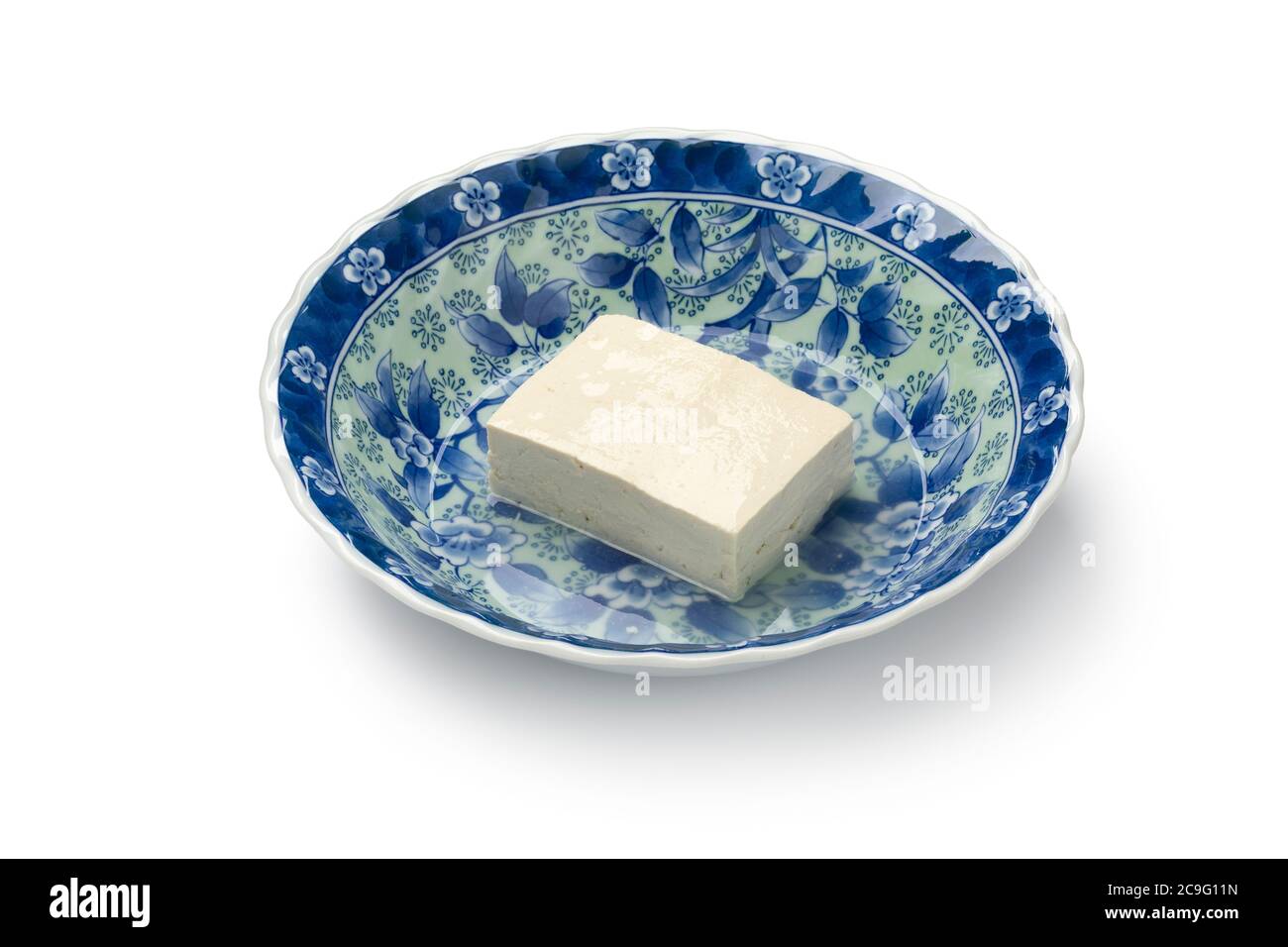 Pezzo di tofu di seta bianca fresca in una ciotola giapponese primo piano con acqua isolata su sfondo bianco Foto Stock