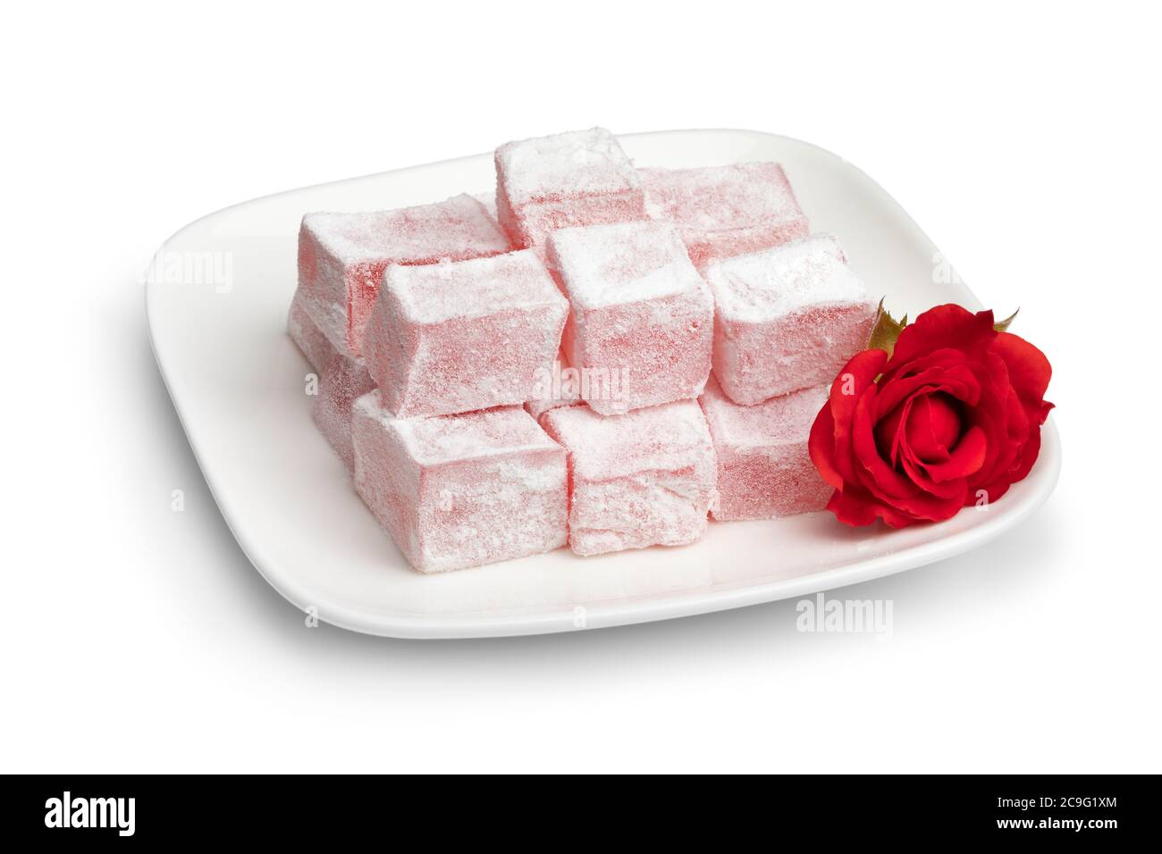 Delizia di rose turche su un piatto bianco e una rosa fresca isolata su sfondo bianco Foto Stock