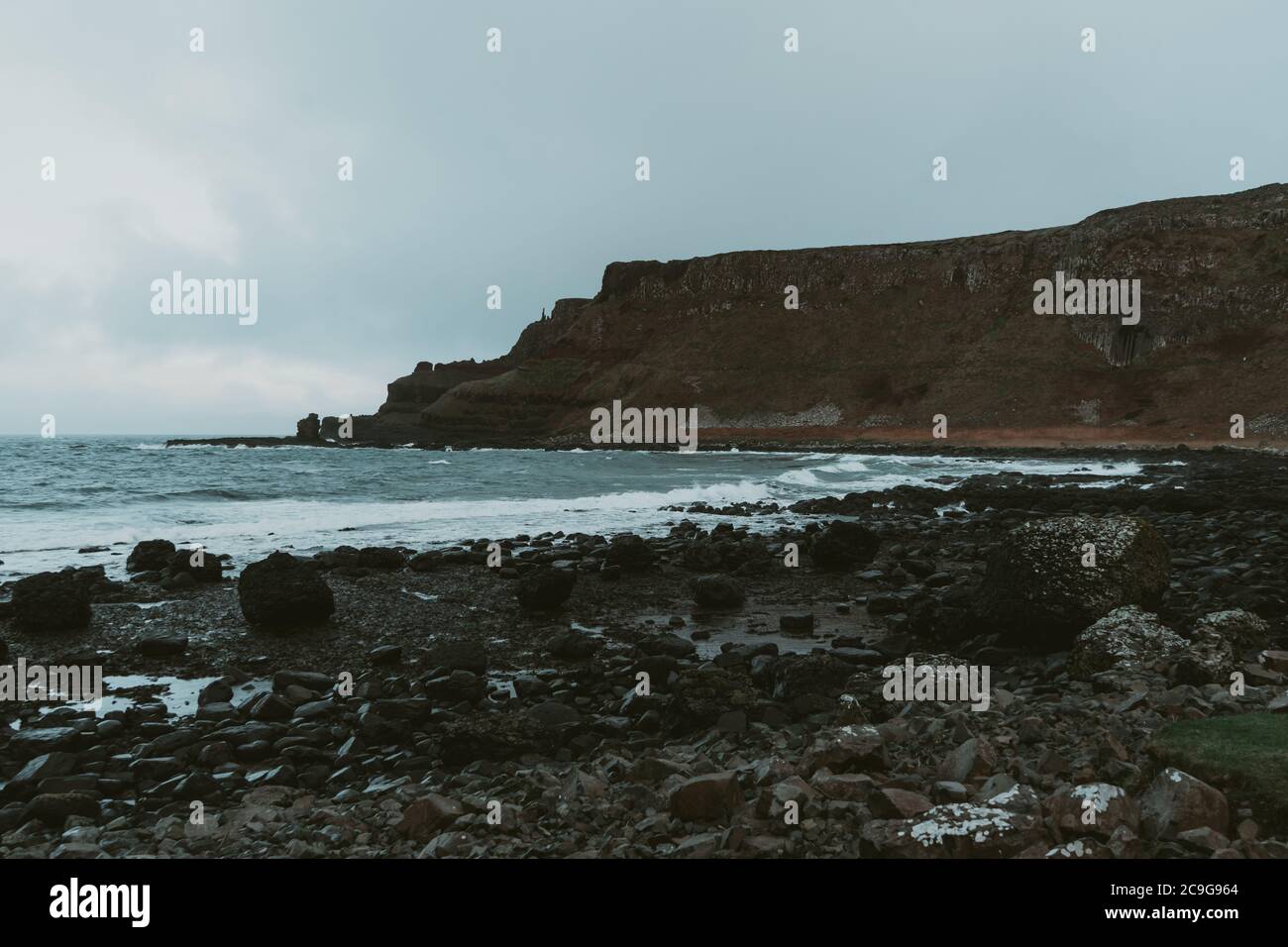 Un rigetto ruvido rompe le onde sulla punta del Selciato dei Giganti, Irlanda Foto Stock