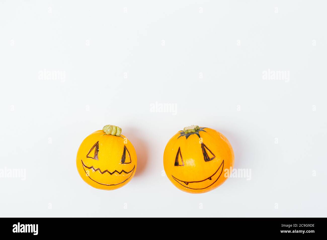 Zucche di Halloween con facce divertenti felici su sfondo bianco, piatto. Foto Stock