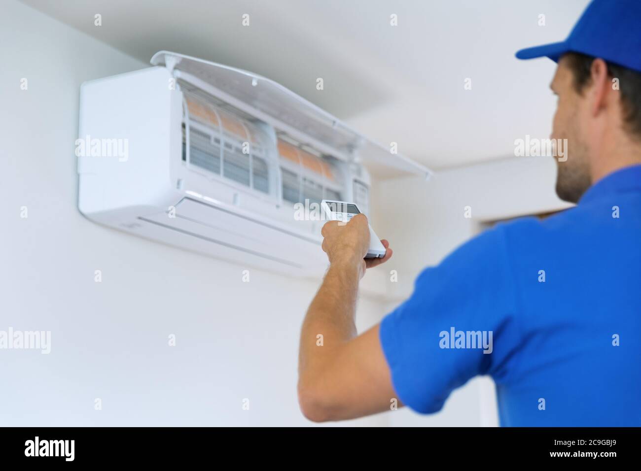 aria condizionata - il lavoratore installa il condizionatore nella stanza Foto Stock