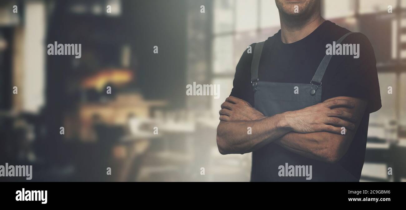 barista in piedi in una caffetteria con le braccia incrociate. copisteria Foto Stock
