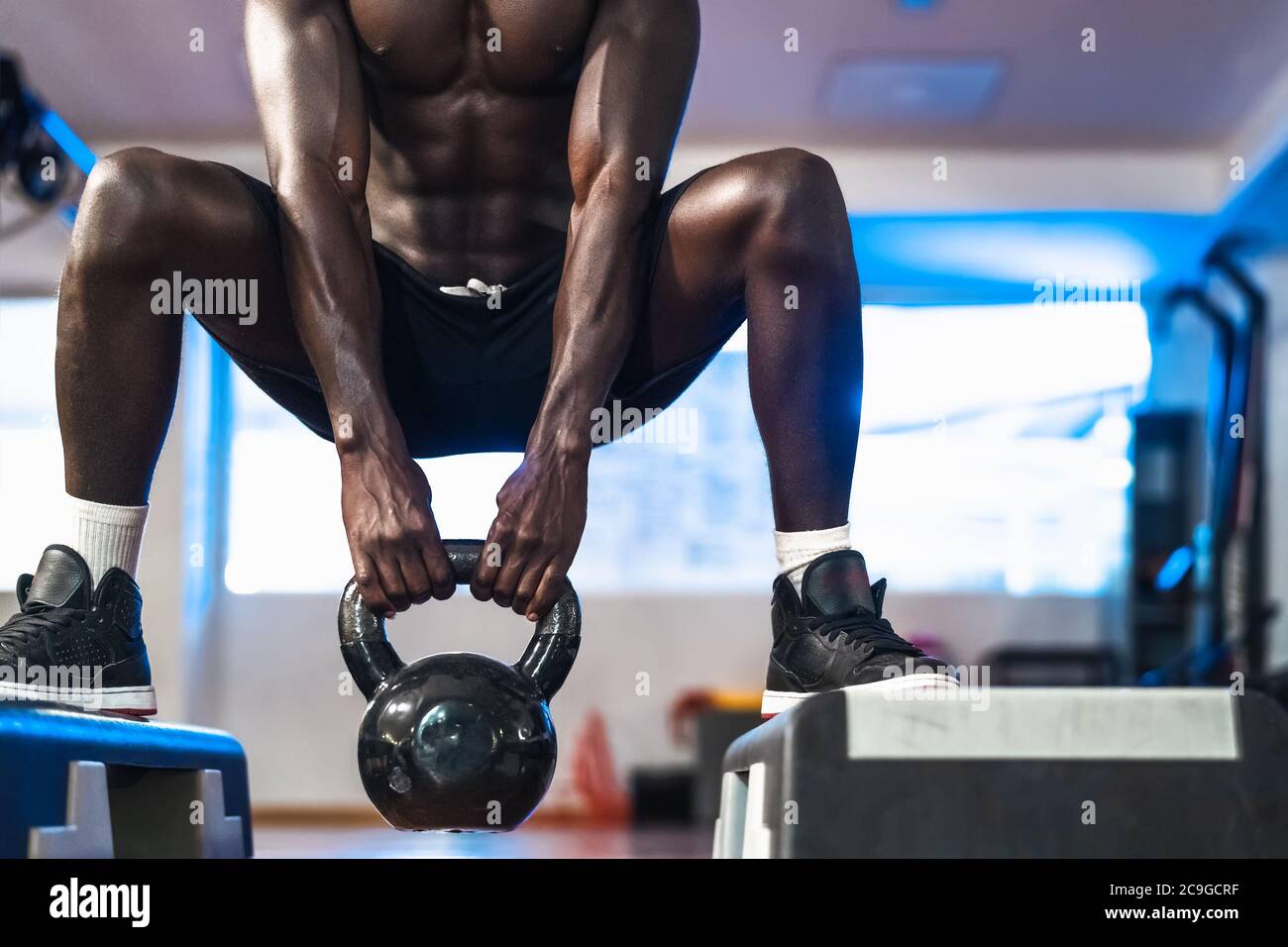 Allenamento giovane uomo africano all'interno della palestra - Fit maschile facendo kettlebell esercizio sessione di allenamento nel centro club sportivo Foto Stock