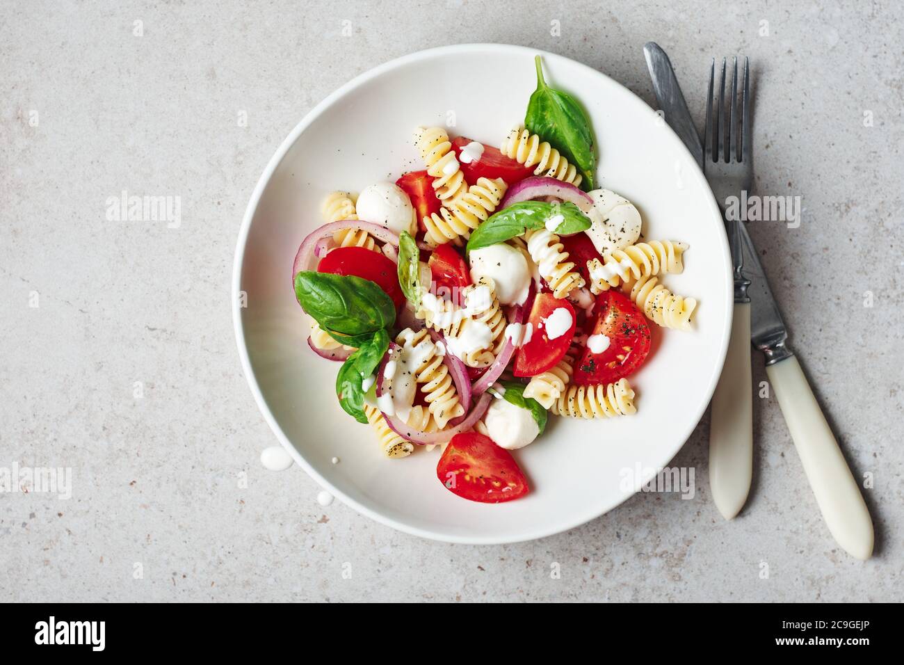 Insalata di pasta con pomodori, mozzarella e foglie di basilico. Foto Stock