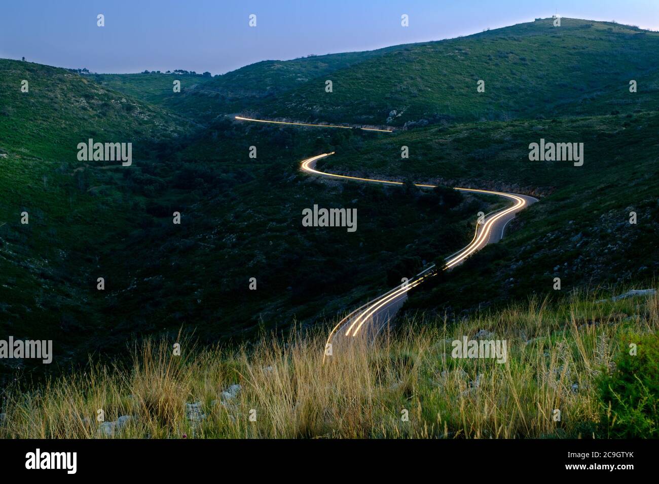 sentiero leggero in auto su strada tortuosa in alta montagna, guida a rischio notturno Foto Stock