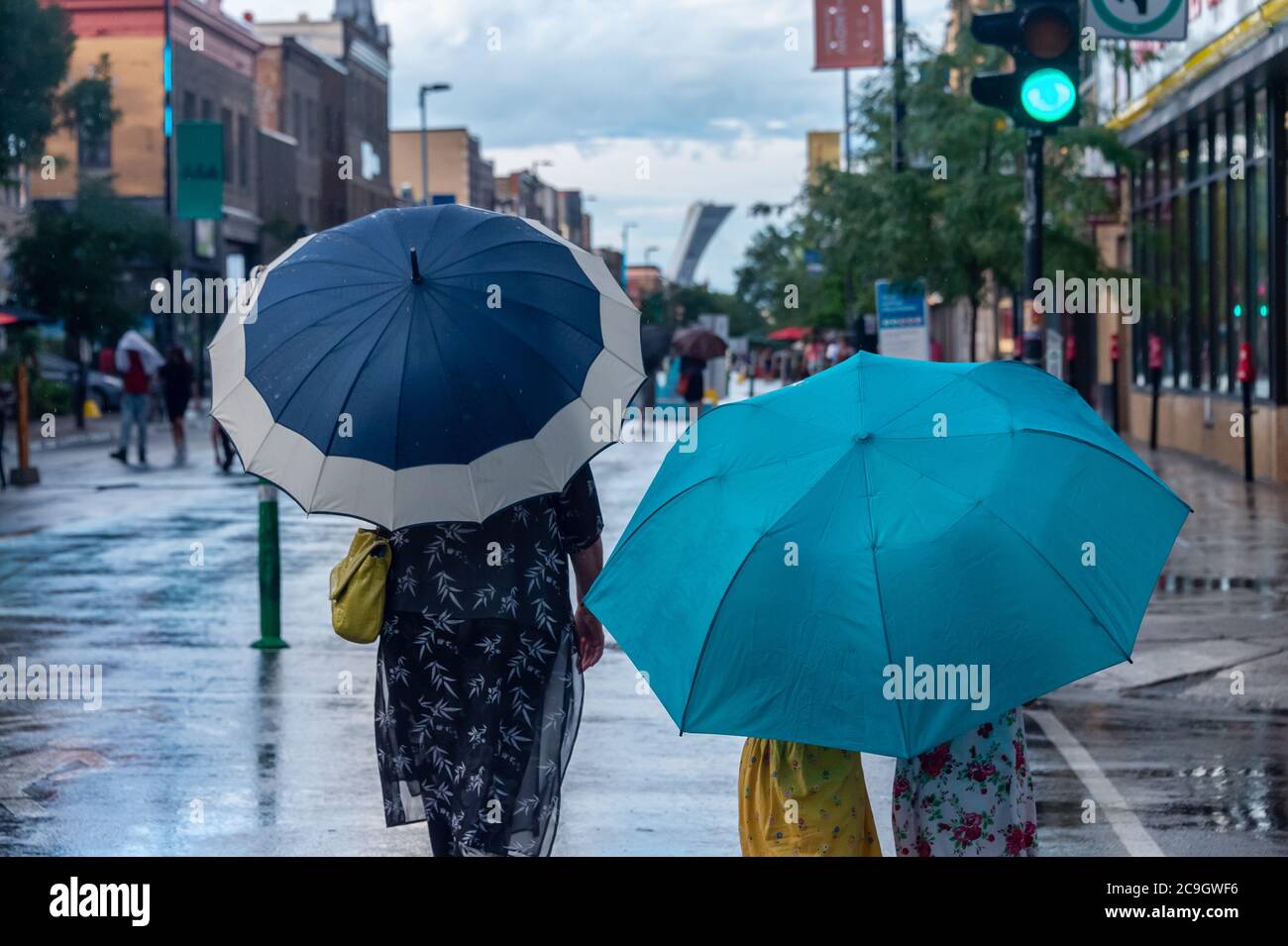 Montreal, CA - 30 luglio 2020: Persone su Mont-Royal Avenue che tengono ombrelloni durante pioggia e tempesta Foto Stock