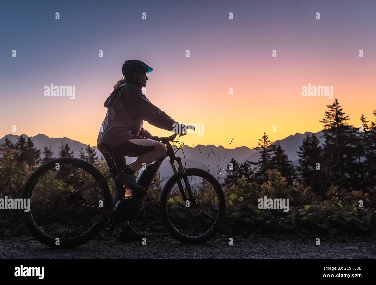 Silhouette di una mountain bike femminile al crepuscolo, dietro scenario montano, Patscherkofel, Patsch, Tirolo, Austria Foto Stock