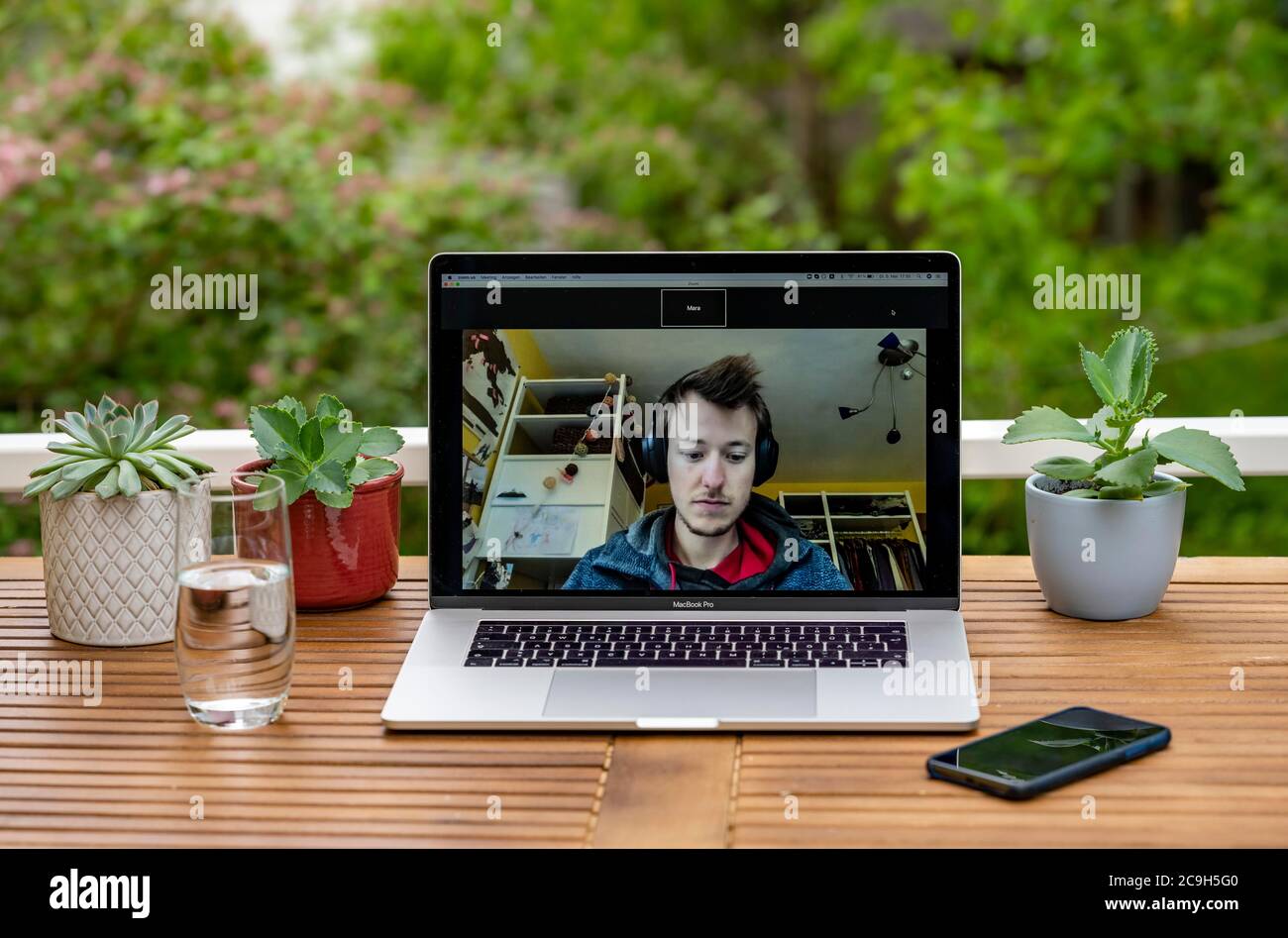 Ufficio domestico con computer portatile, Apple MacBook Pro e iPhone X alla scrivania, con applicazione Zoom durante una videoconferenza, Germania Foto Stock
