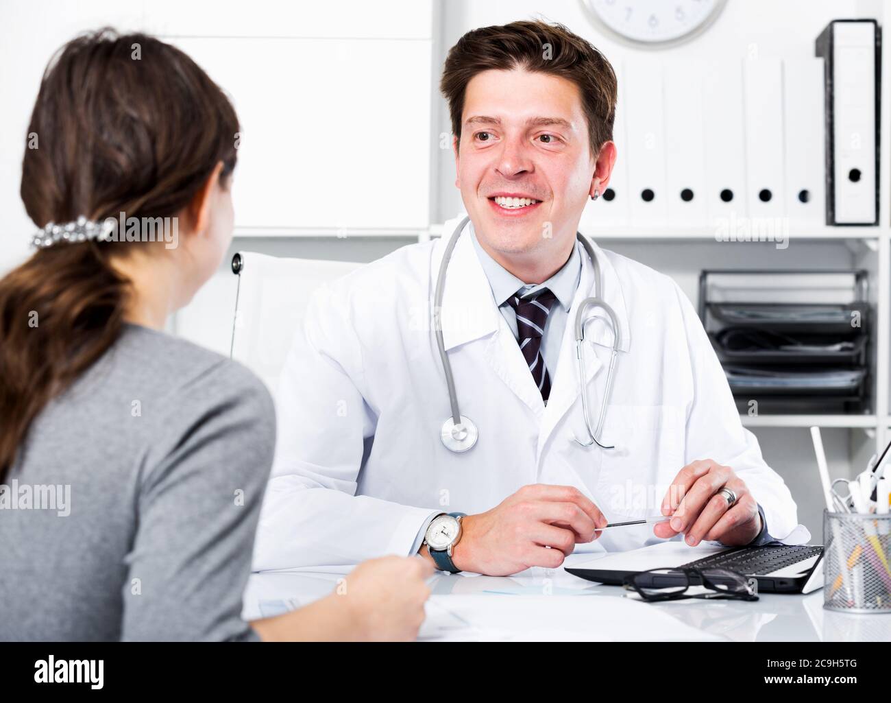 Ritratto di giovane medico divertente con paziente seduto al tavolo Foto Stock