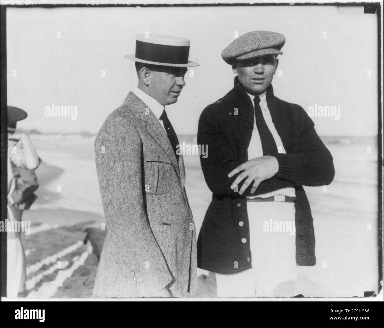 Jack Dempsey al suo campo di allenamento, giugno 1921- in piedi sulla spiaggia con l'uomo; indossare un cappuccio visored Foto Stock