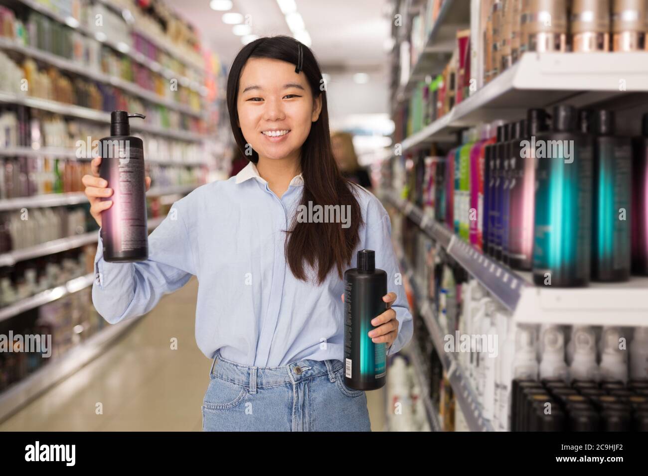 Sorridente cliente asiatico donna che acquista condizionatore per capelli  in negozio di prodotti per la cura dei capelli Foto stock - Alamy