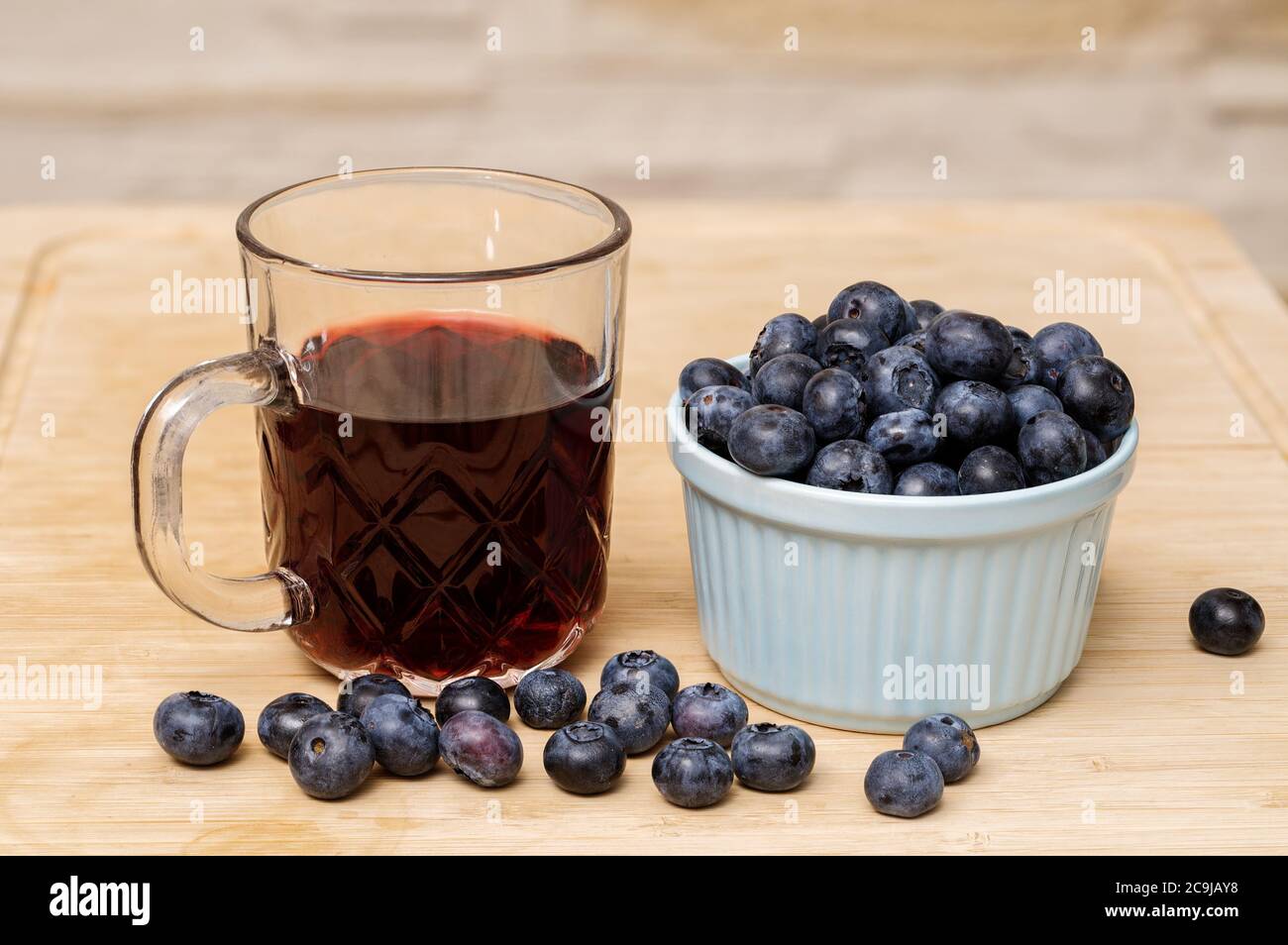 mirtilli maturi in una ciotola, un bicchiere di succo di mirtillo, fotografati da vicino, Foto Stock