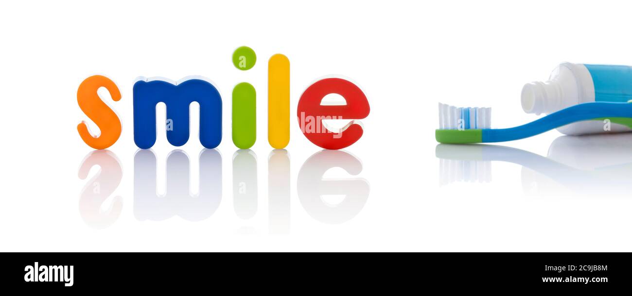 La parola "sorriso" in lettere multicolore con uno spazzolino da denti, su sfondo bianco. Foto Stock