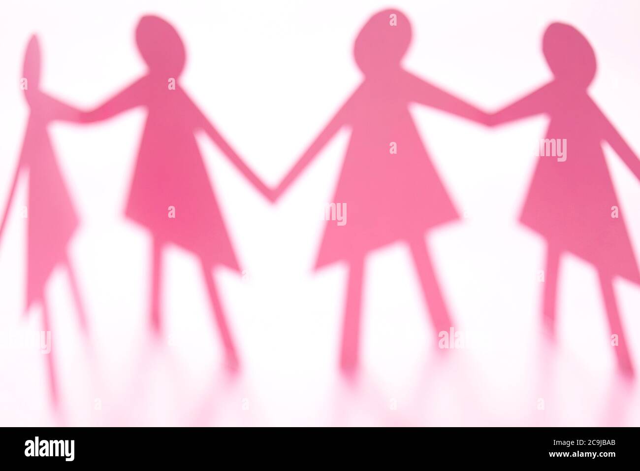 Figure femminili della catena di carta con taglio rosa su sfondo bianco. Foto Stock