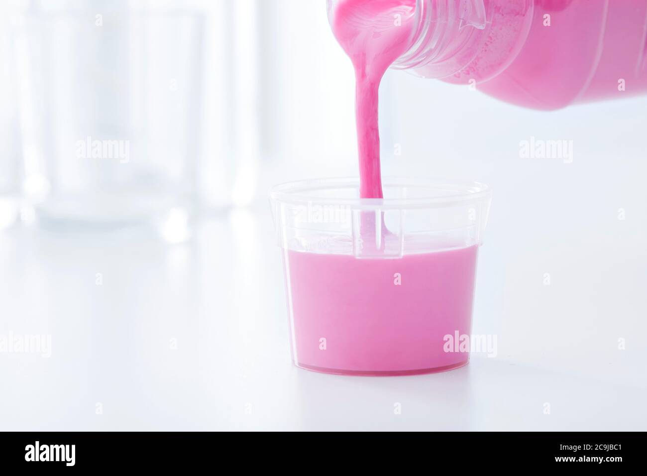 Medicinale antiacido versato in un bicchiere dosatore. Foto Stock