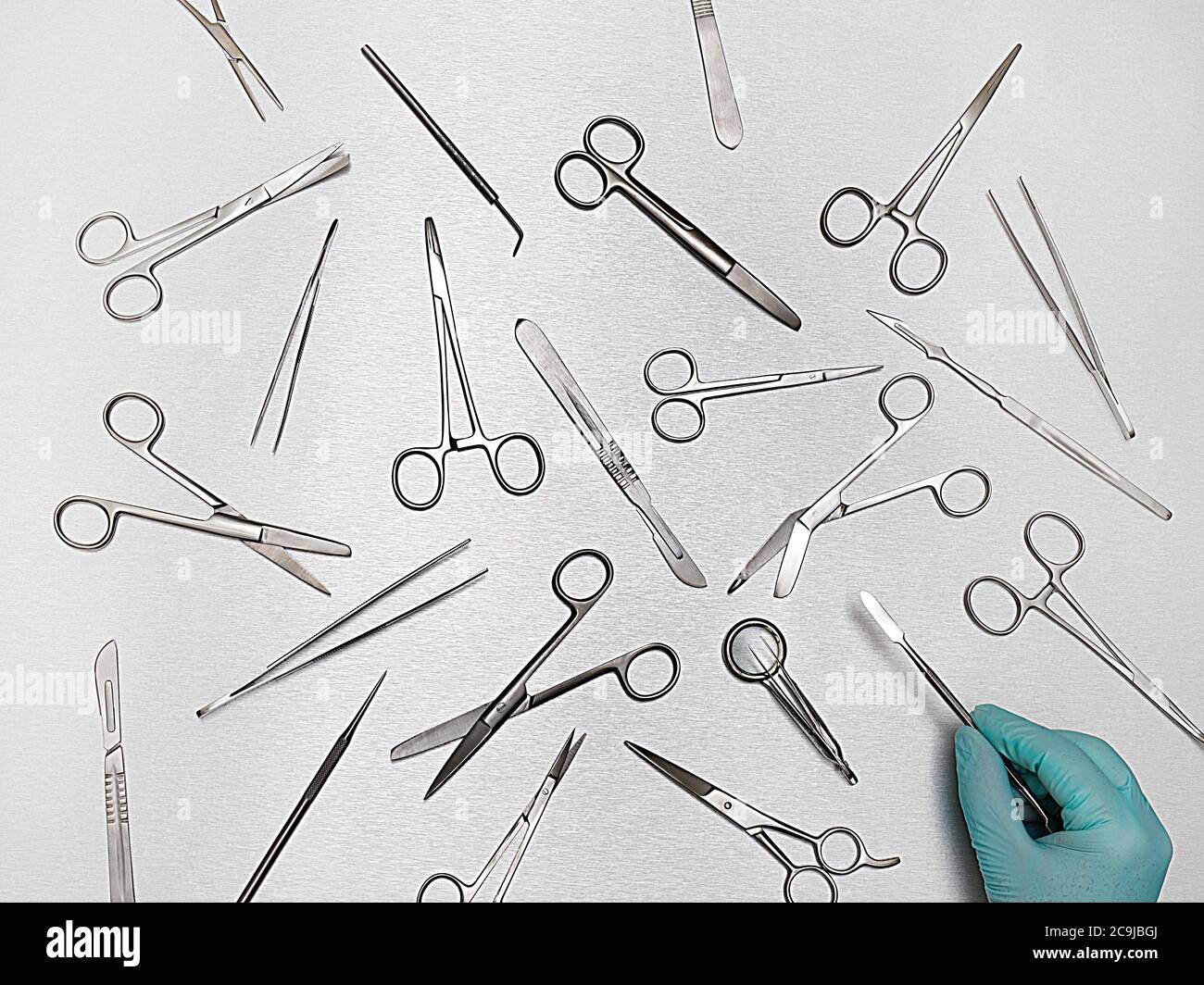 Persona che seleziona l'apparecchiatura chirurgica su sfondo grigio. Foto Stock