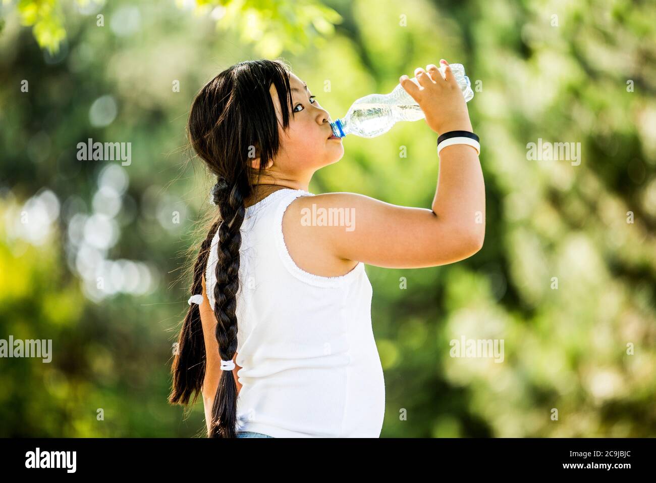 Ragazza che beve acqua da bottiglia di plastica in parco, ritratto. Foto Stock