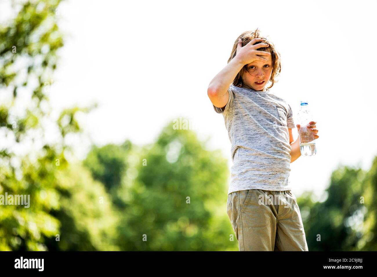 Ragazzo che tiene una bottiglia d'acqua nel parco, ritratto. Foto Stock
