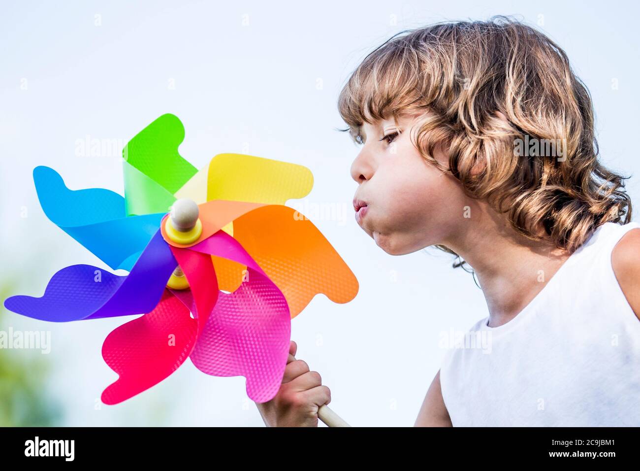 Ragazzo soffiando colorato mulino a vento di carta nel parco. Foto Stock