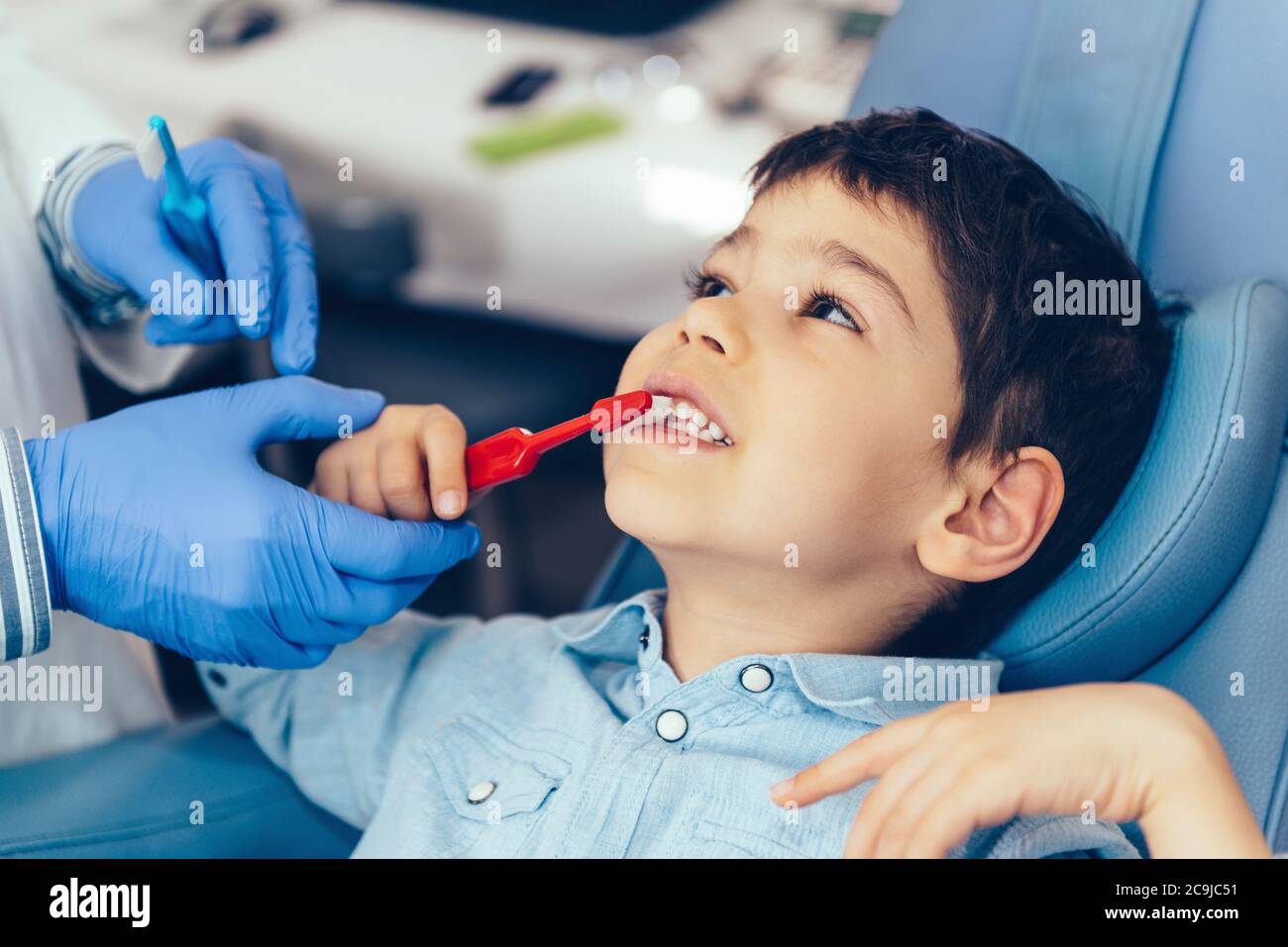 Dentista che insegna a un ragazzo l'igiene dentale. Foto Stock