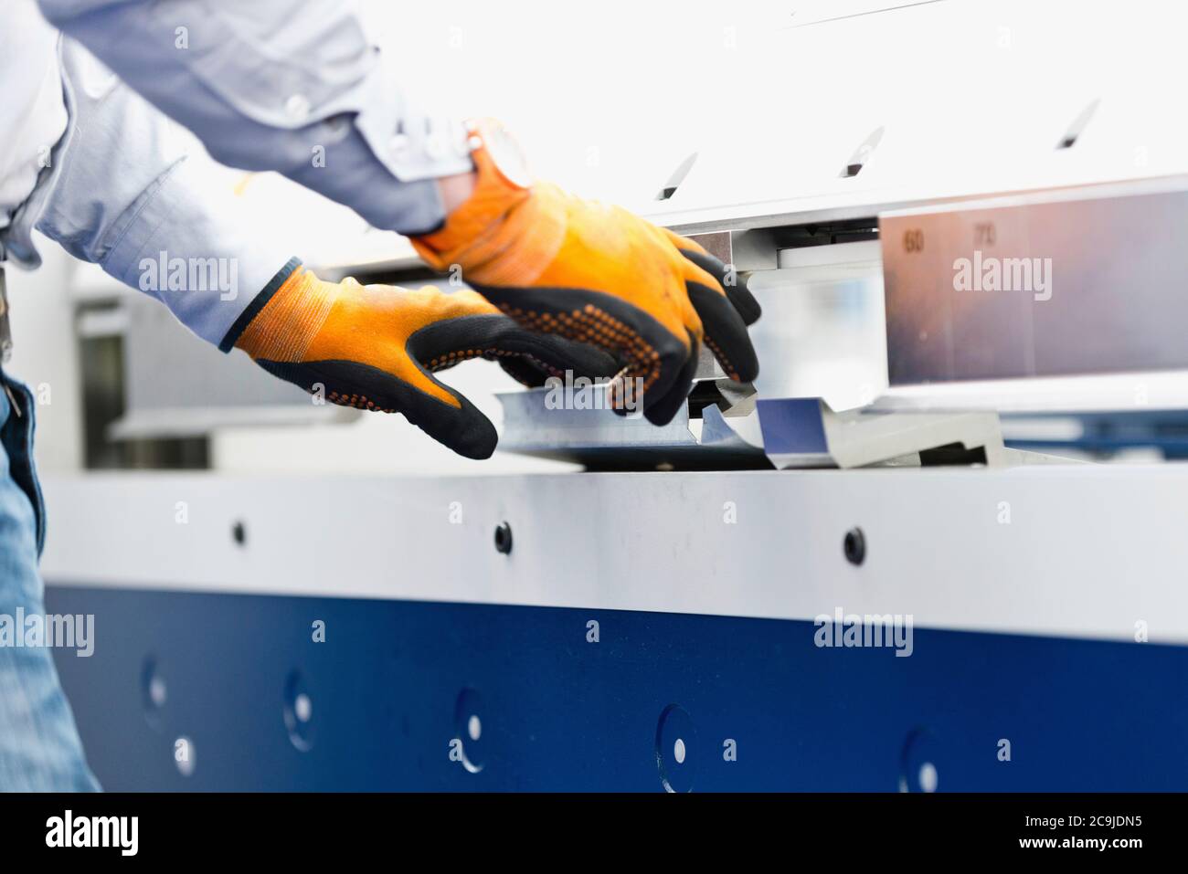 Operatore che lavora su macchine piegatrici industriali per stagno. Foto Stock