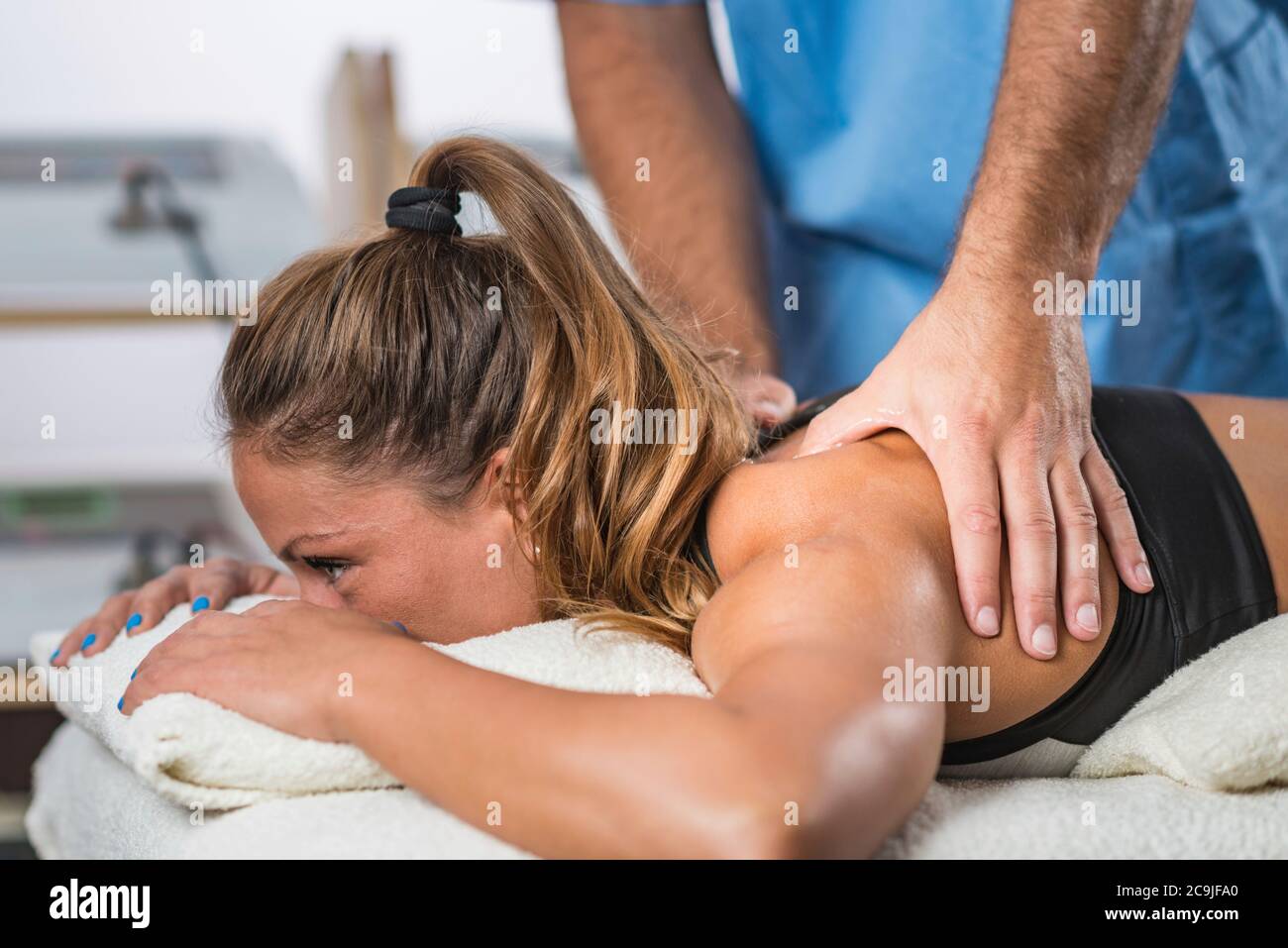 Terapia fisica. Terapista che applica una forte pressione ai muscoli delle spalle. Foto Stock Terapia fisica. Terapista che applica una forte pressione ai muscoli delle spalle. Foto Stock