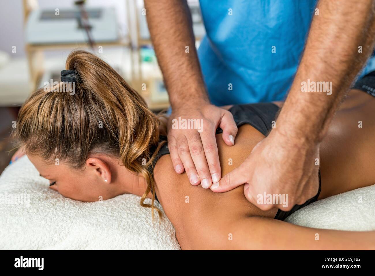 Osteopatia. Terapista che applica una forte pressione ai muscoli delle spalle. Foto Stock Osteopatia. Terapista che applica una forte pressione ai muscoli delle spalle. Foto Stock