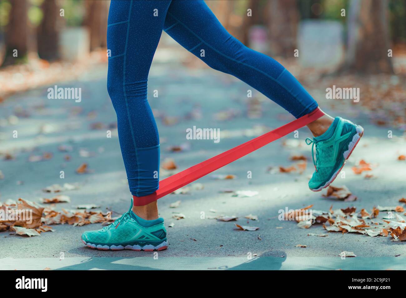 Donna che si esercita con la banda di resistenza in un parco. Foto Stock