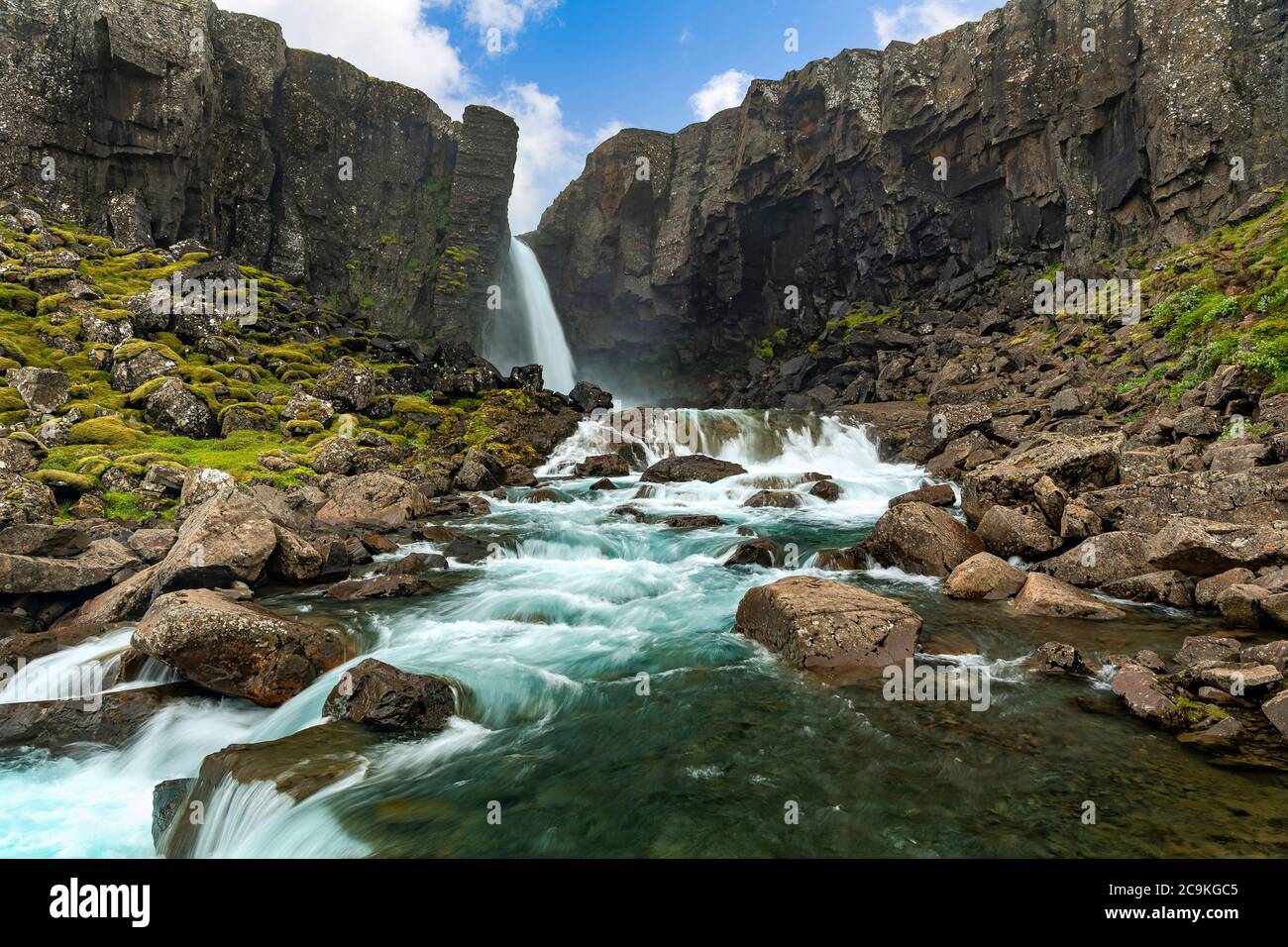 Una misteriosa cascata nascosta nella natura nella campagna islandese, montagne rocciose con muschio e torrenti turchesi. Che ha un flusso potente. Foto Stock
