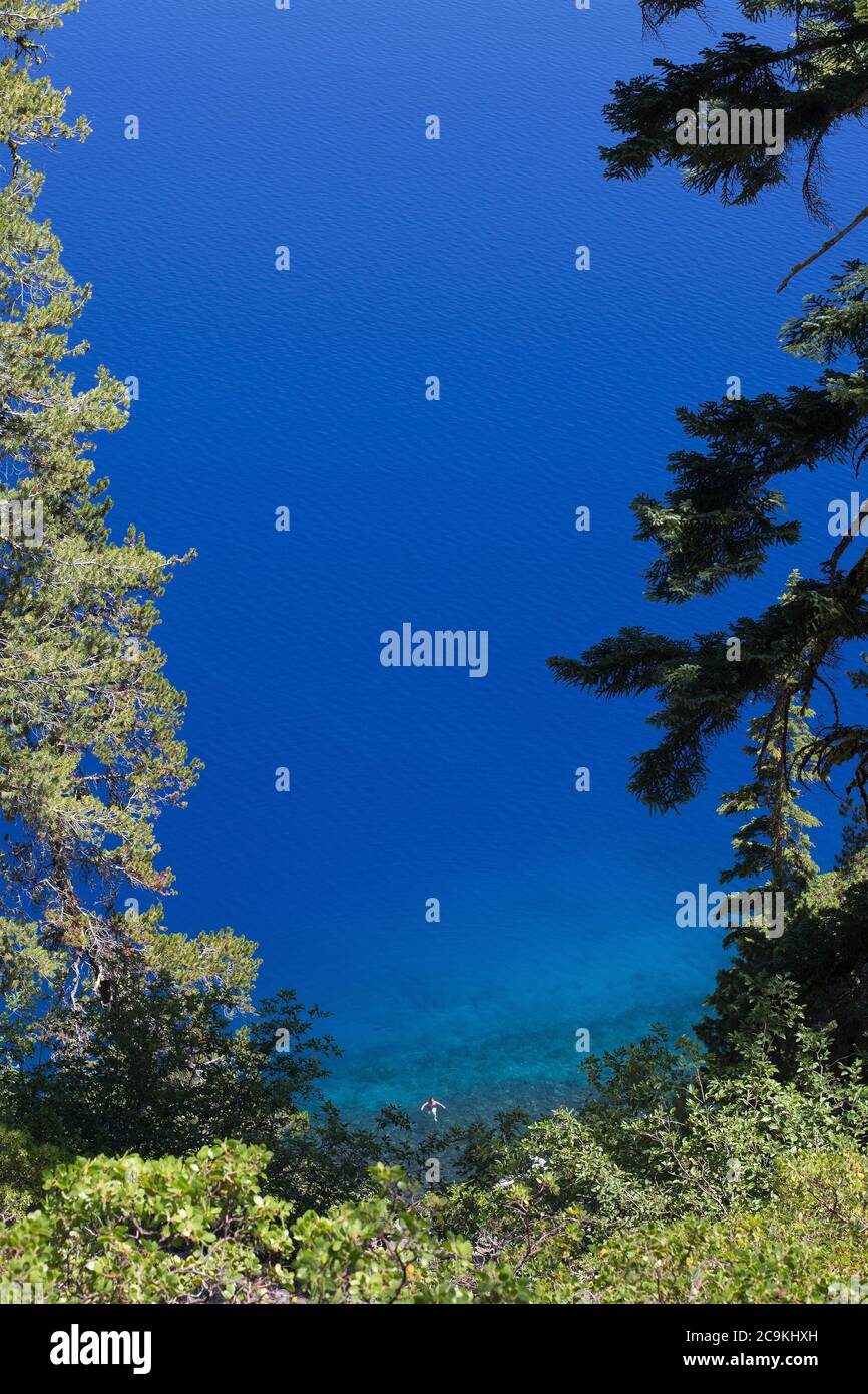 Una vista aerea di una persona che nuota da sola nelle acque blu del Crater Lake, in Oregon, Stati Uniti. Foto Stock