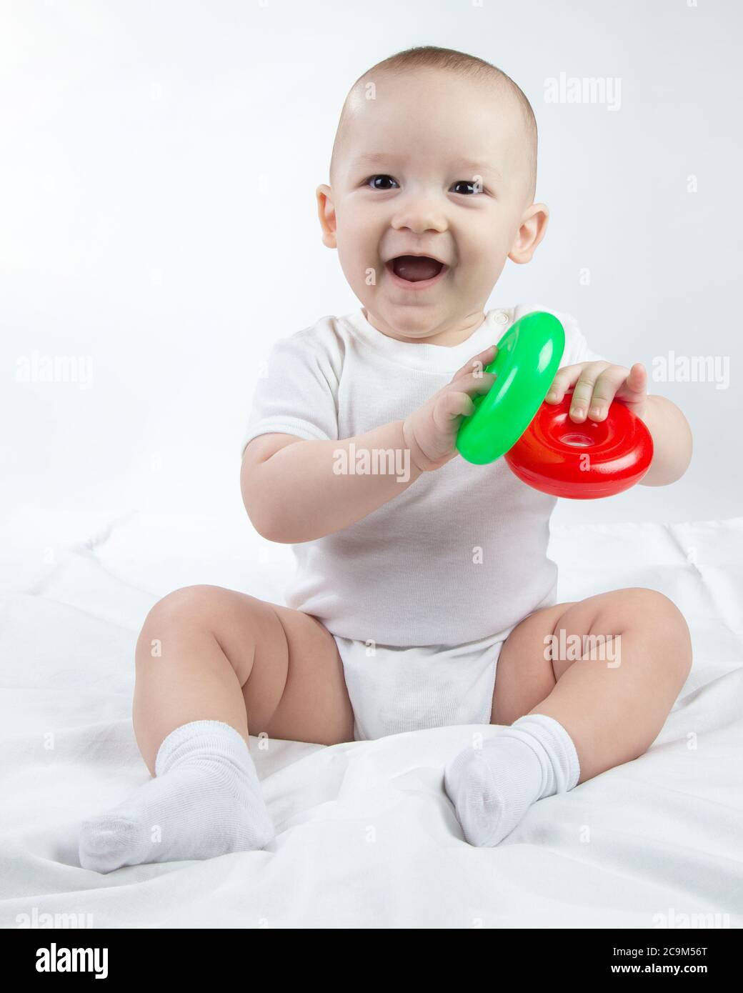 Foto di un bambino sorridente di nove mesi con giocattoli luminosi Foto Stock