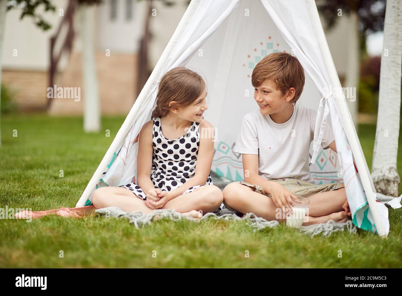 Ragazzo e ragazza seduti in tenda in una giornata di sole Foto Stock