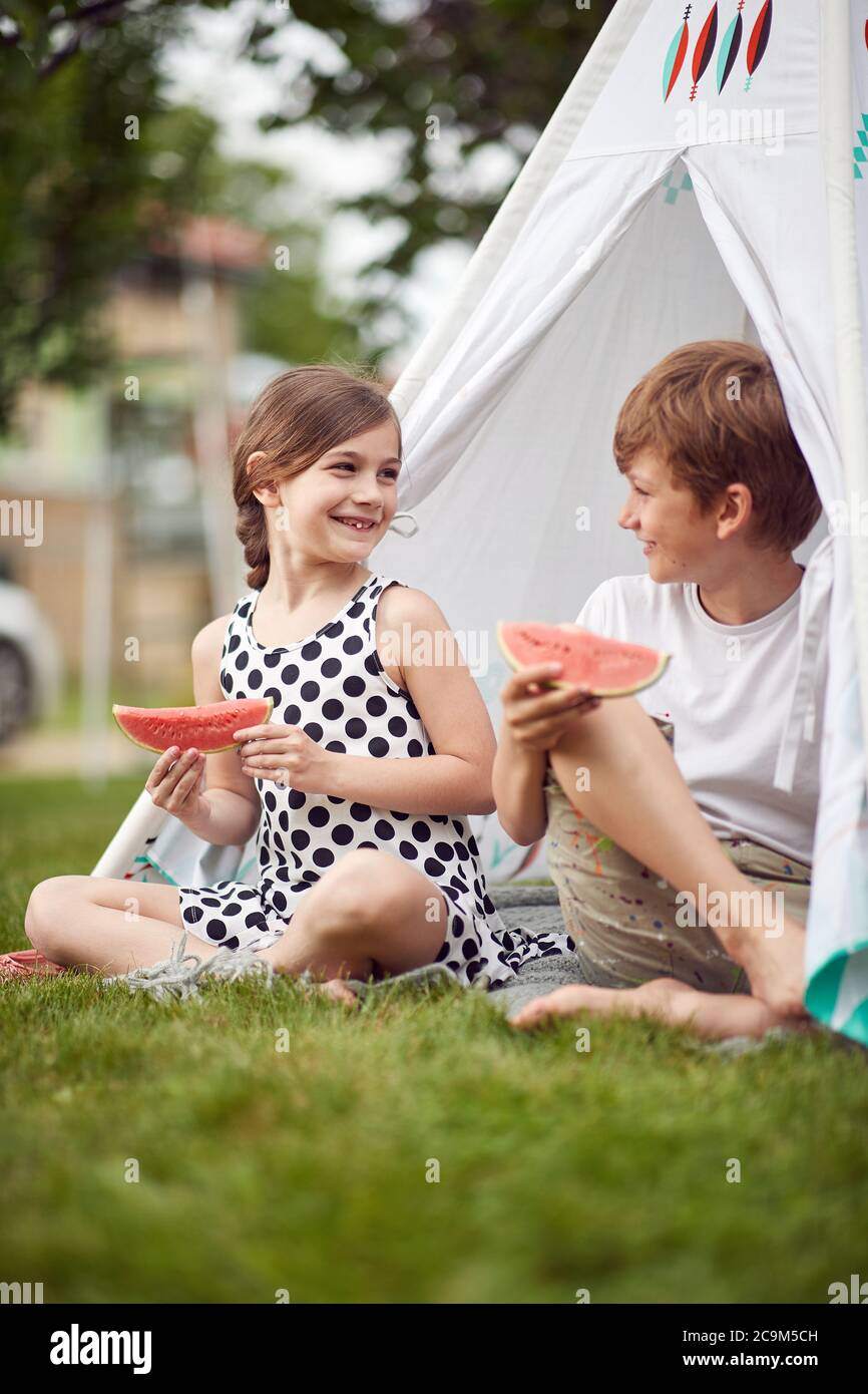 I bambini mangiano l'anguria in un accampamento in una bella giornata Foto Stock
