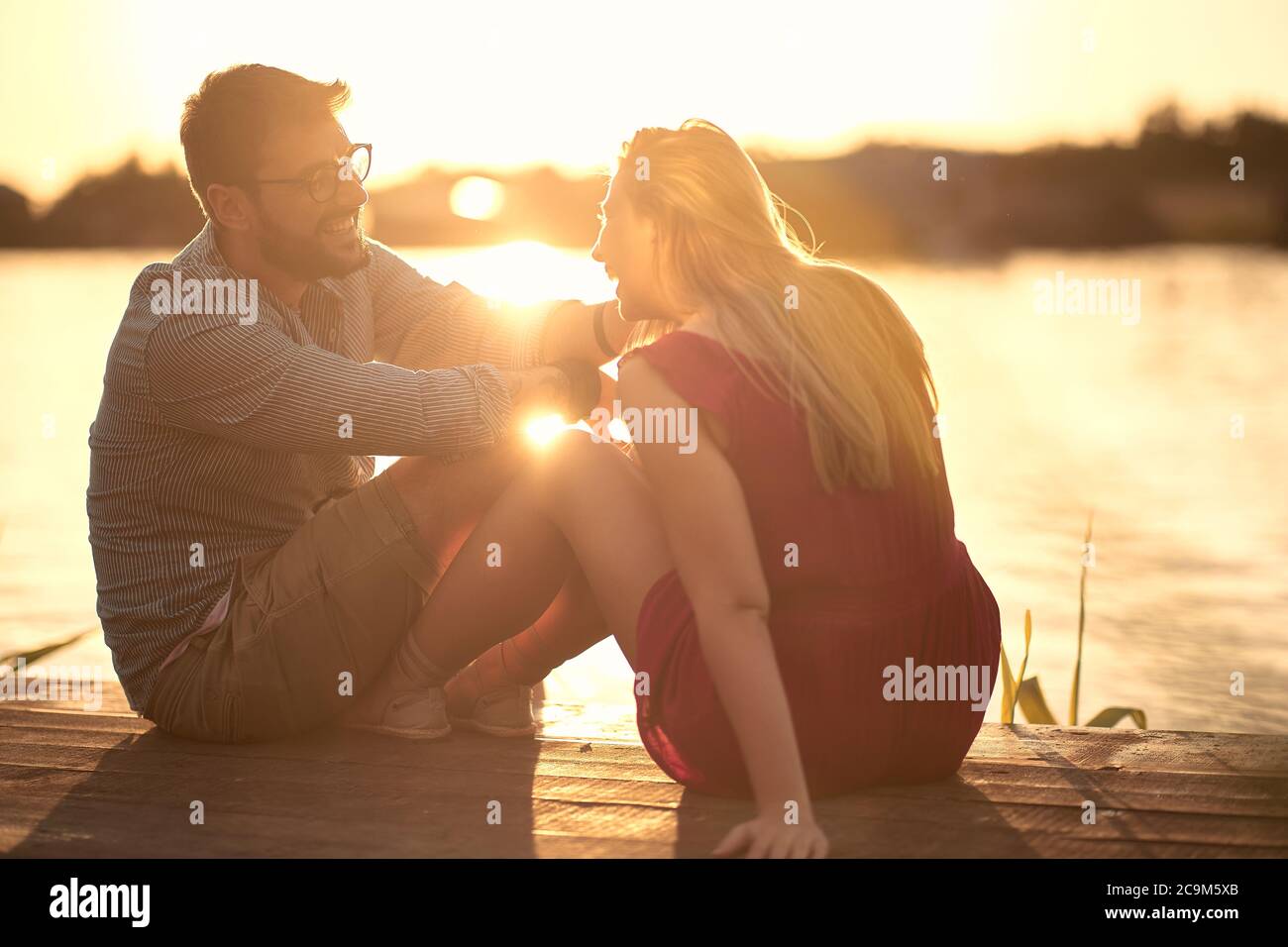 Sorridendo uomo e donna innamorati. Romantico tramonto sul lago. Foto Stock